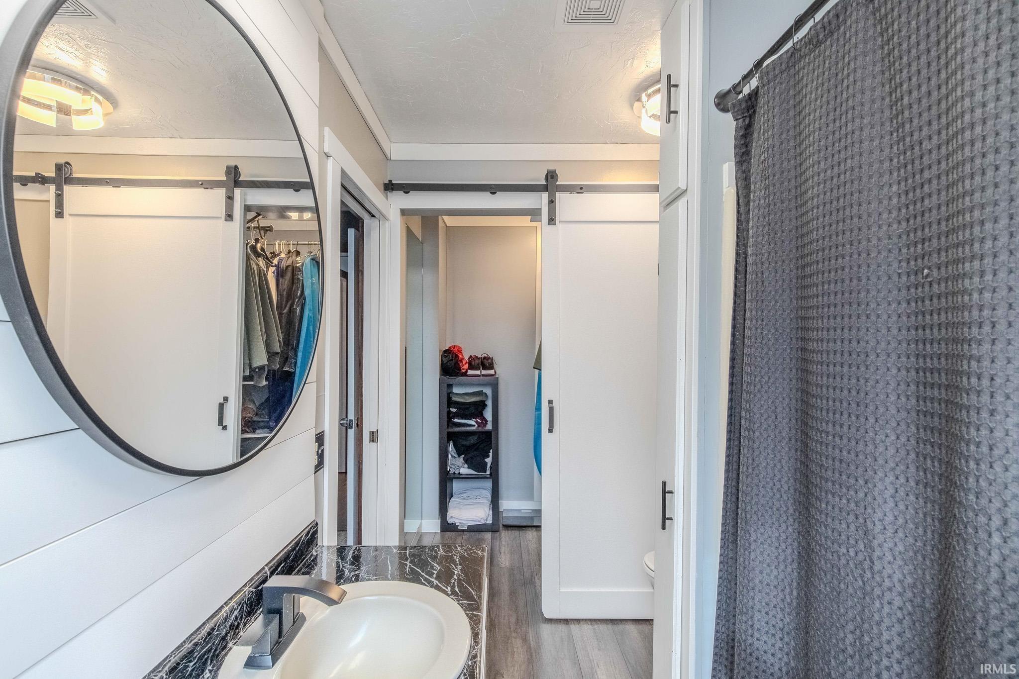 Full bathroom featuring a shower with curtain and dark wood-style floors