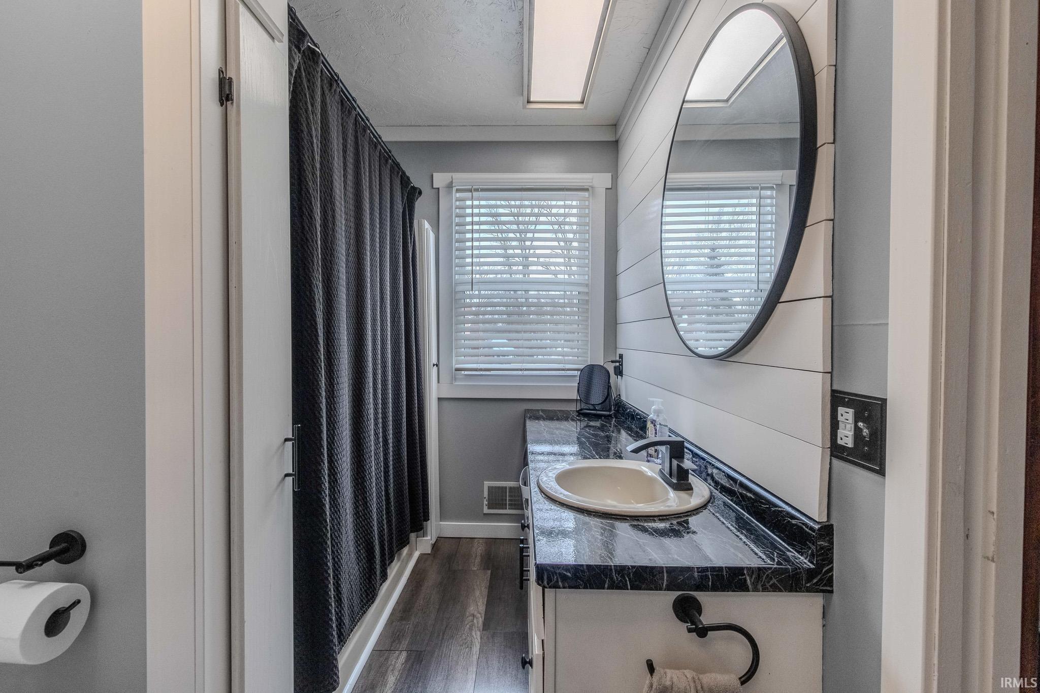 Full bath with a shower with curtain, vanity, and dark wood finished floors