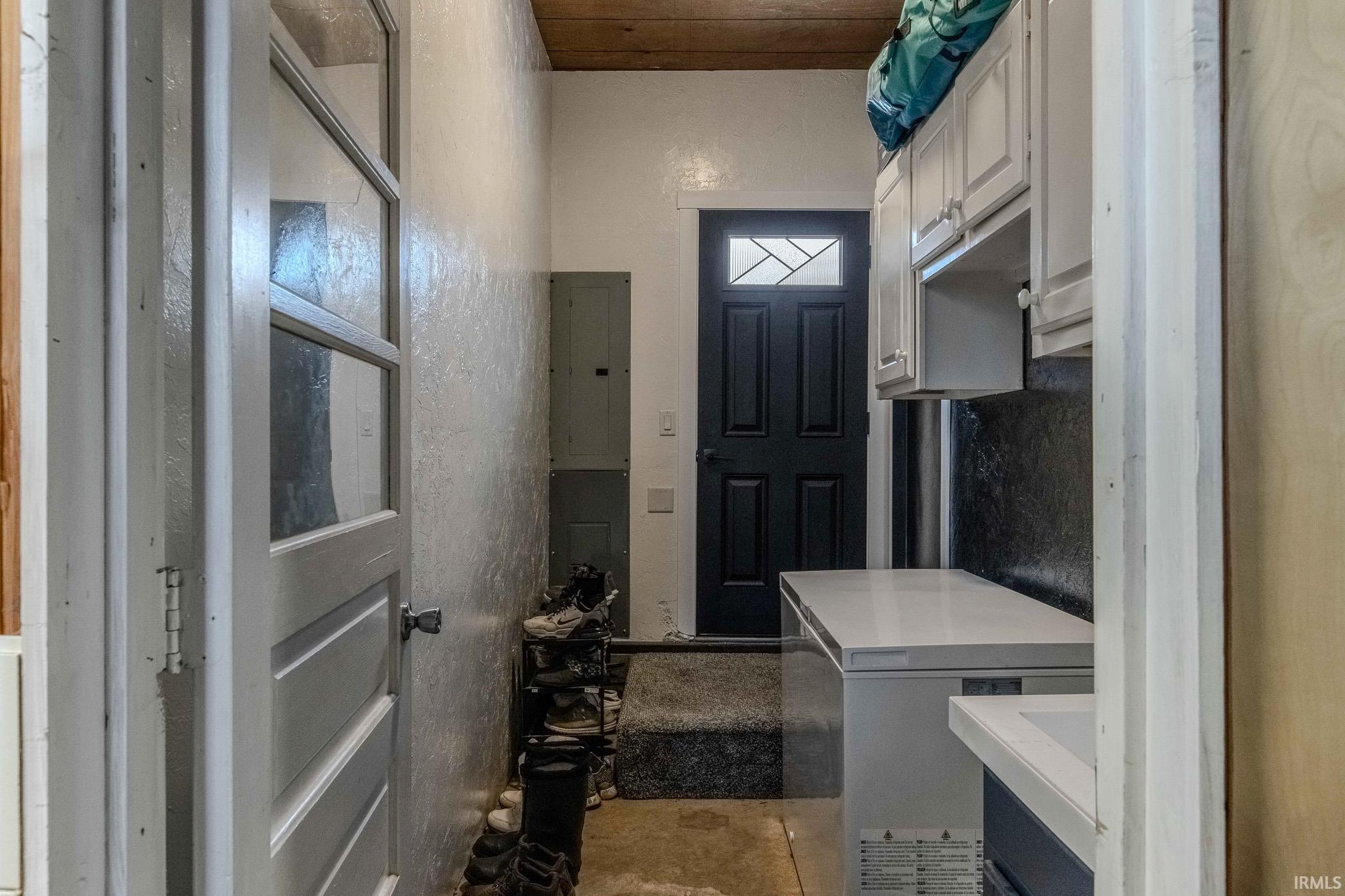 Laundry room featuring electric panel and concrete flooring