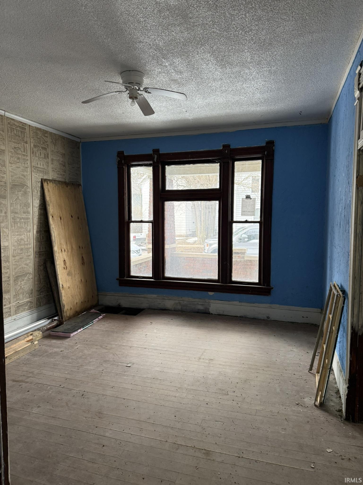 Unfurnished room featuring wood-type flooring, a ceiling fan, and a textured ceiling