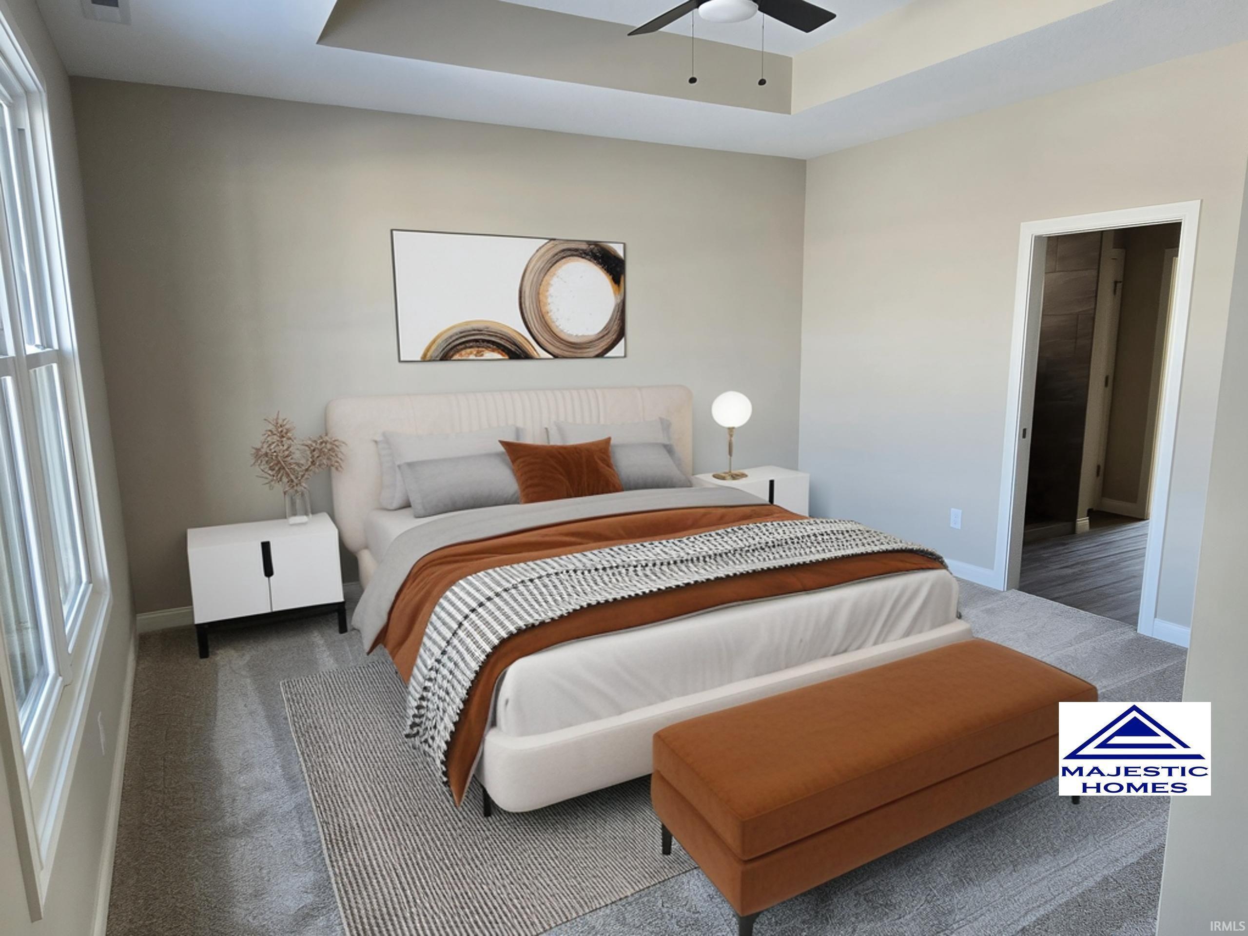 Carpeted bedroom with a raised ceiling and ceiling fan