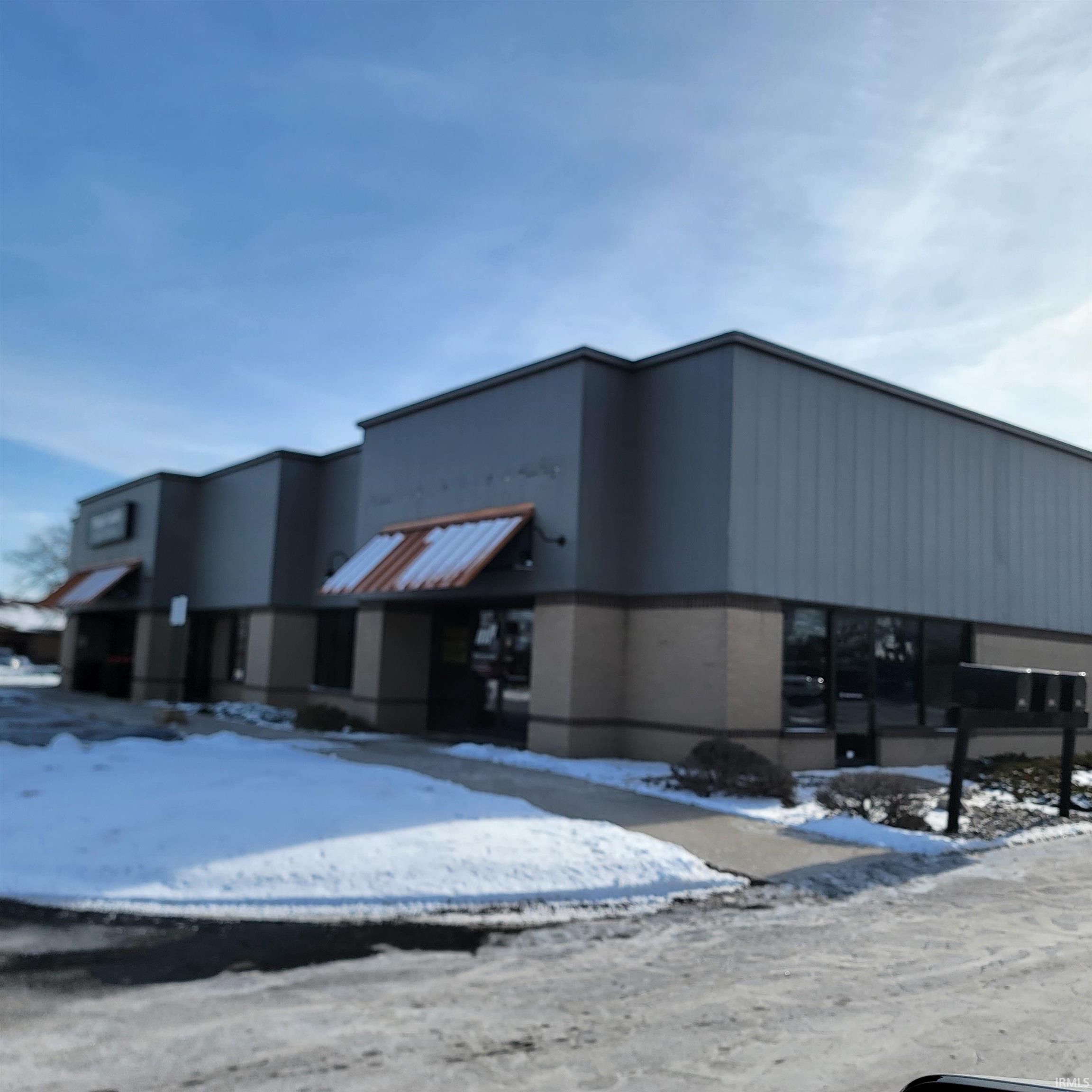 Snow covered property with view of commercial area