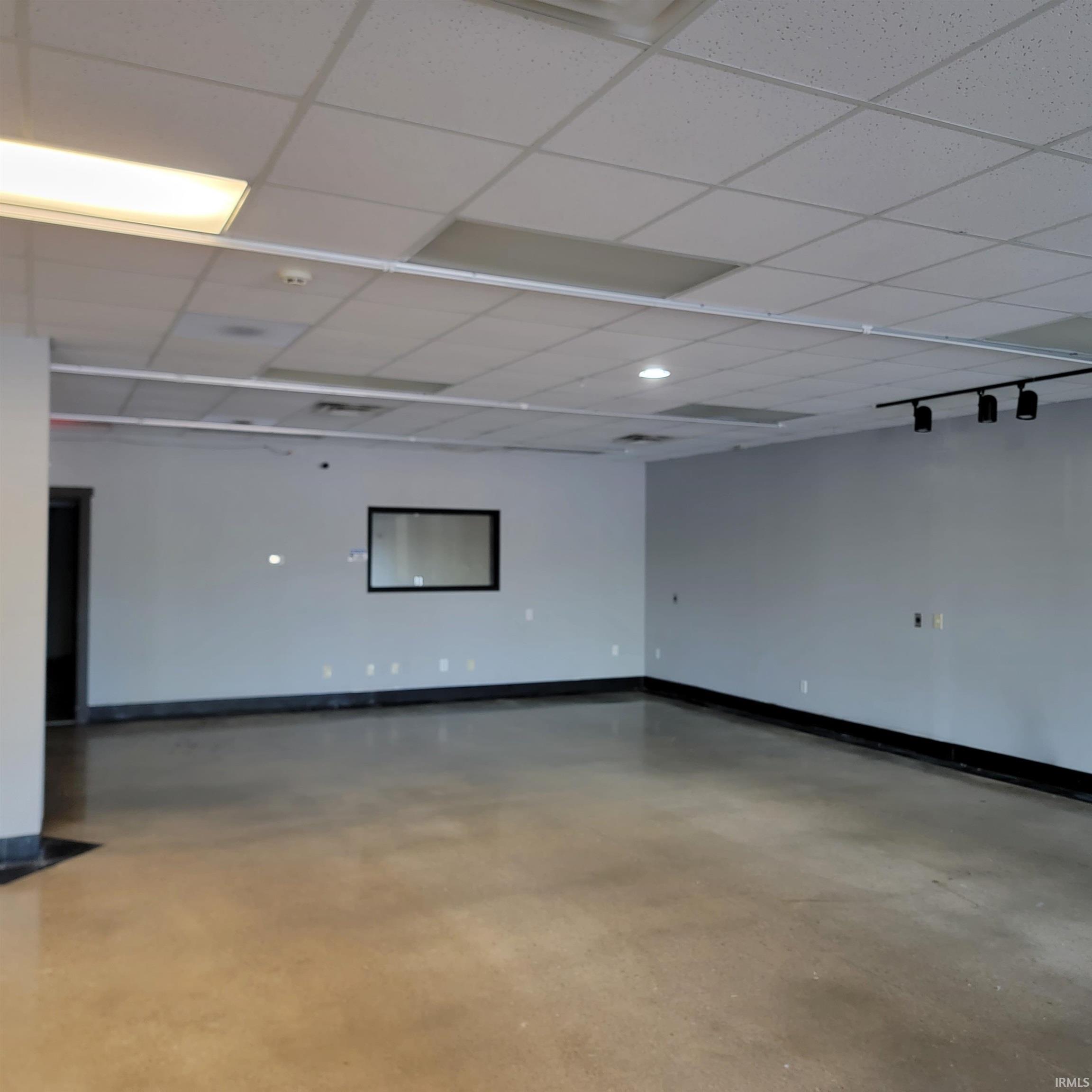 Empty room with a paneled ceiling and concrete flooring
