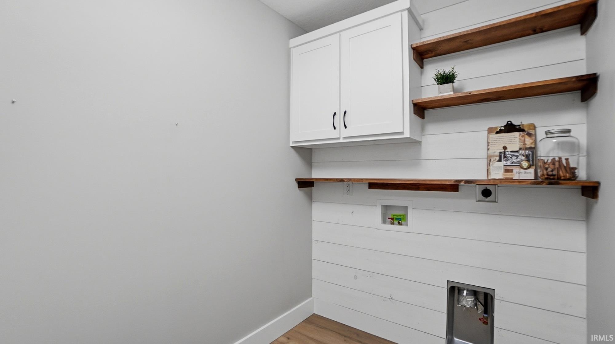 Laundry area with cabinet space, electric dryer hookup, washer hookup, and light wood-type flooring