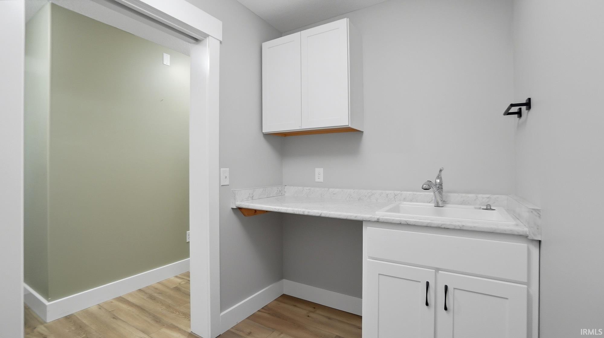 Laundry room with a sink and light wood-style floors