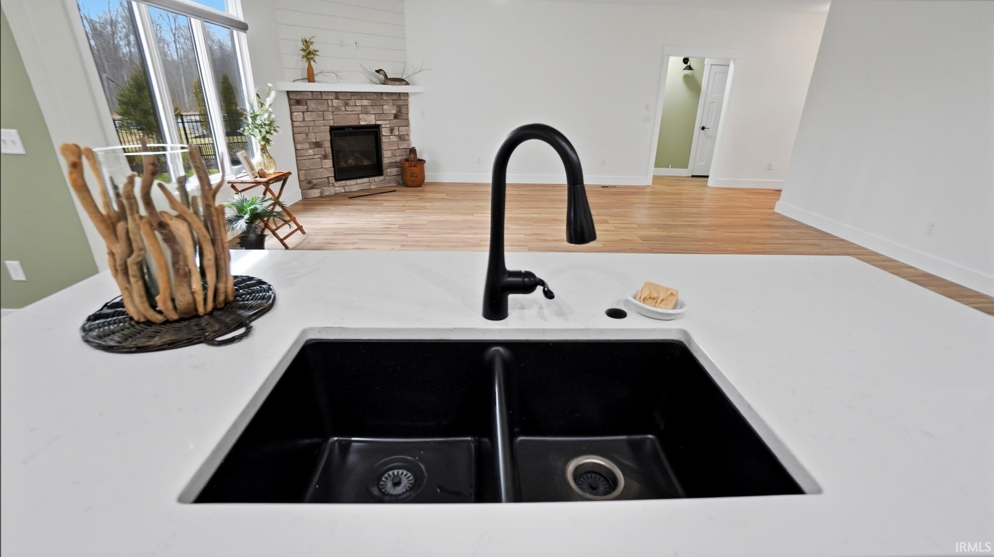 Kitchen view of a fireplace, light stone countertops, and wood finished floors