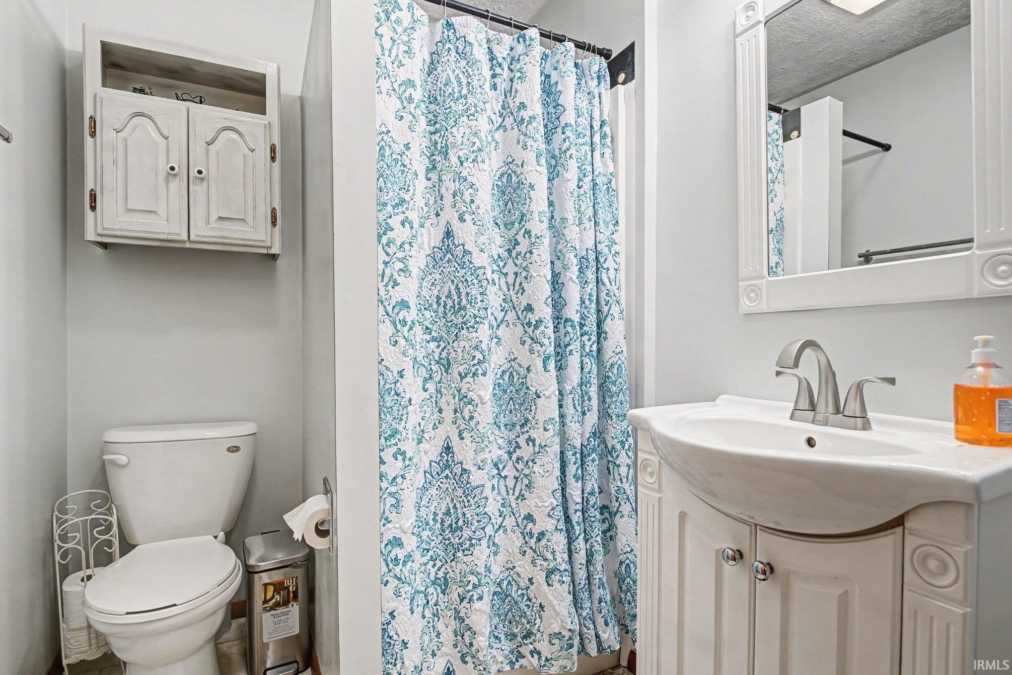Full bath with vanity, a shower with shower curtain, and a textured ceiling