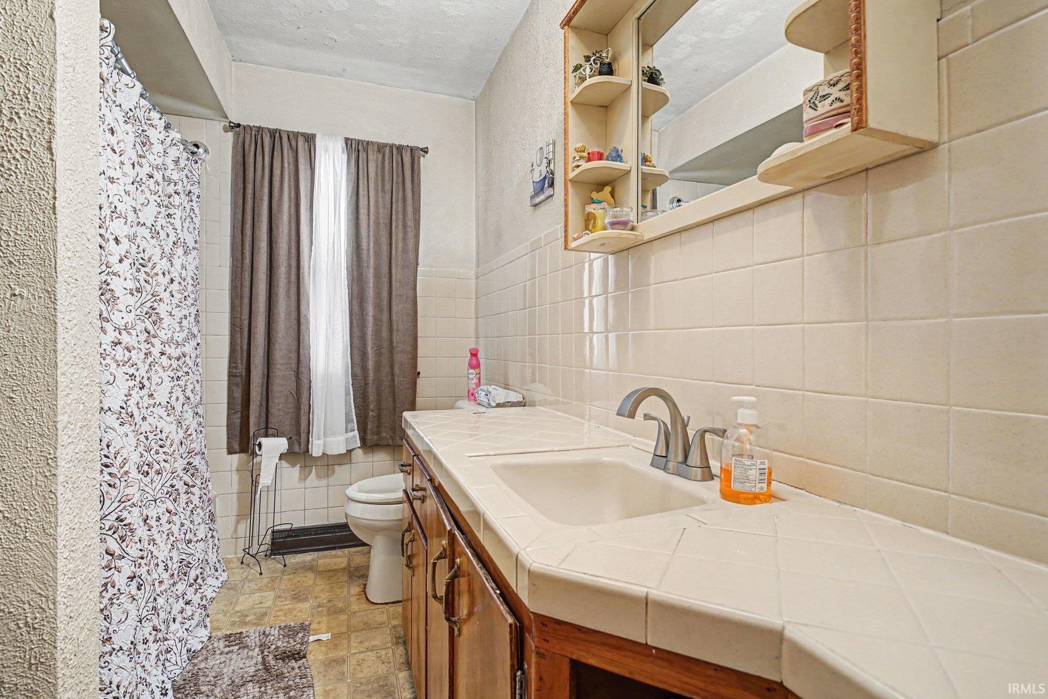Full bathroom with vanity, a shower with curtain, and tile walls