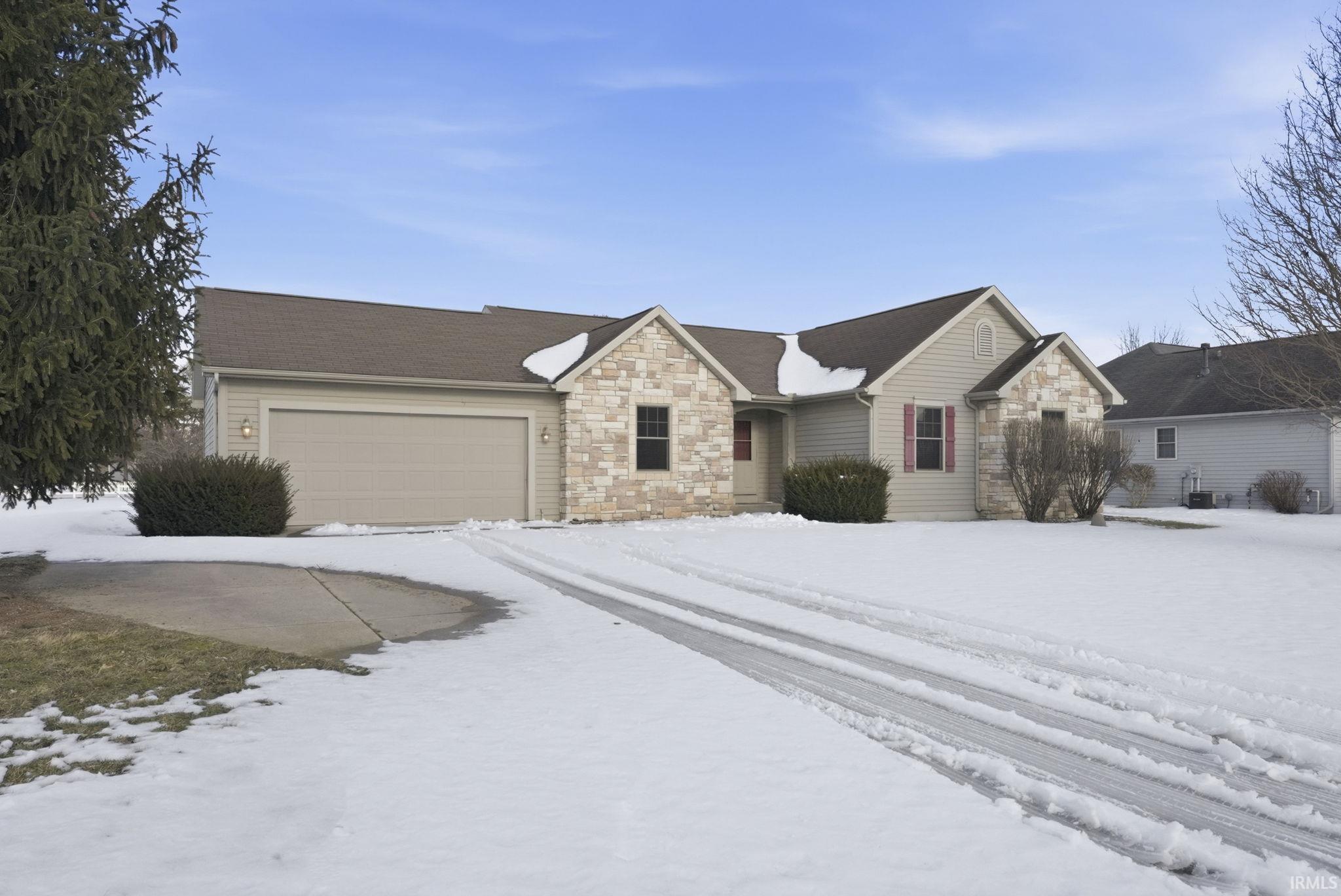 Ranch-style house with stone siding and an attached garage