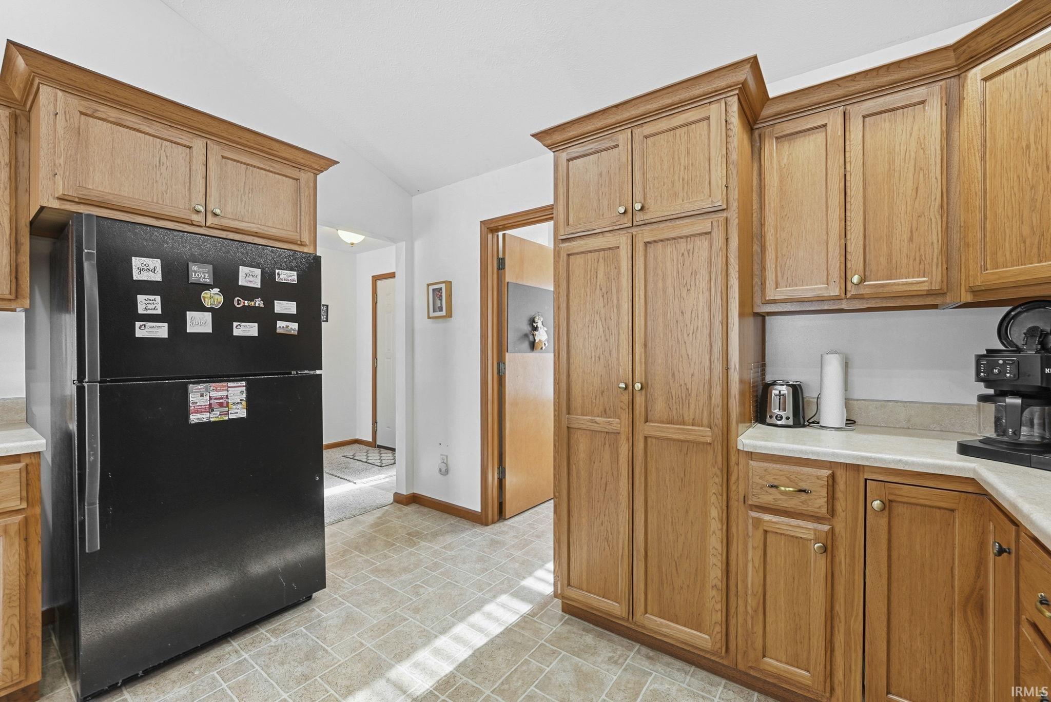 Kitchen featuring freestanding refrigerator, light countertops, and wood finish cabinetry