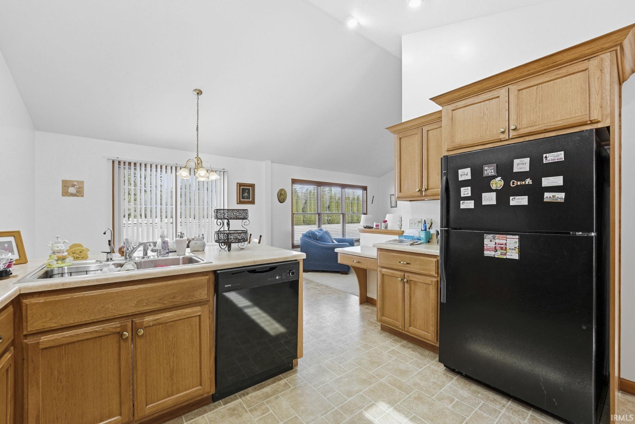 Kitchen with black appliances, light countertops, lofted ceiling, and a peninsula