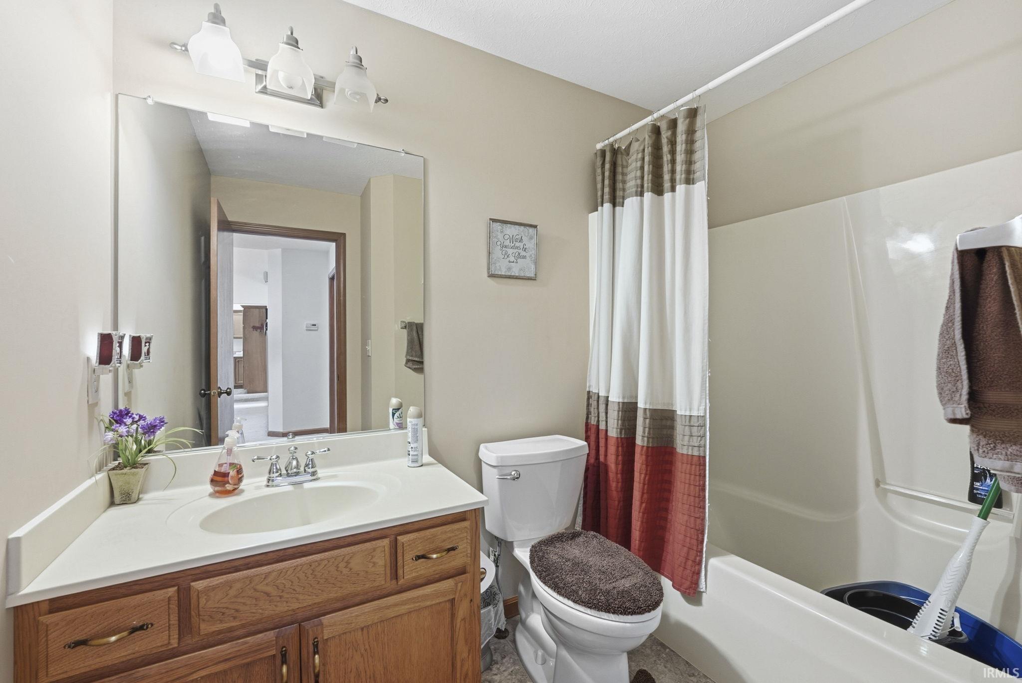 Bathroom featuring vanity and shower / bath combination with curtain