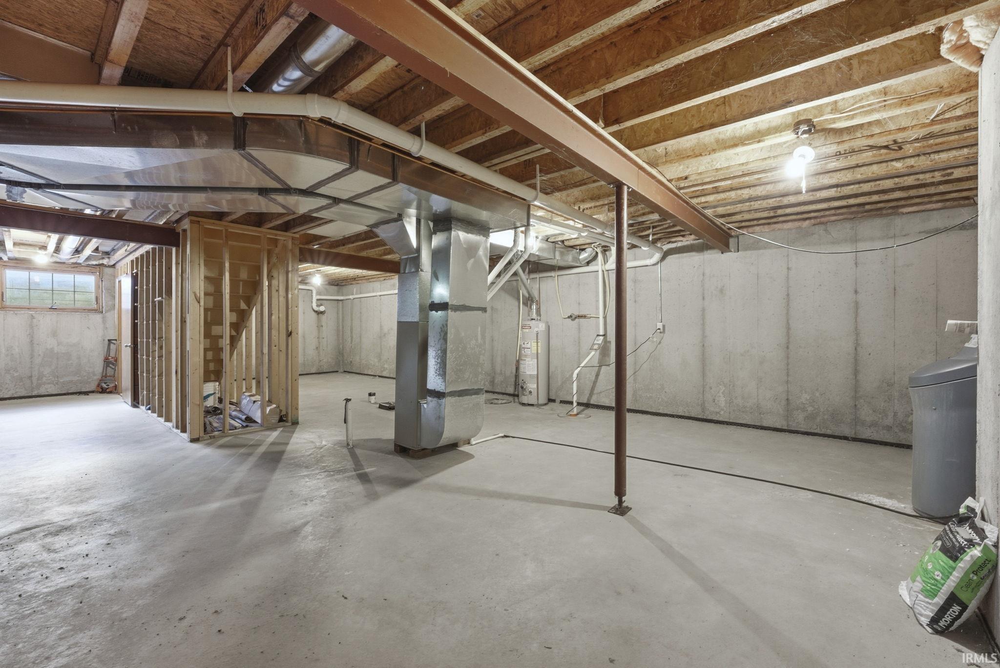 Unfinished basement featuring a water softener, heating unit, and water heater