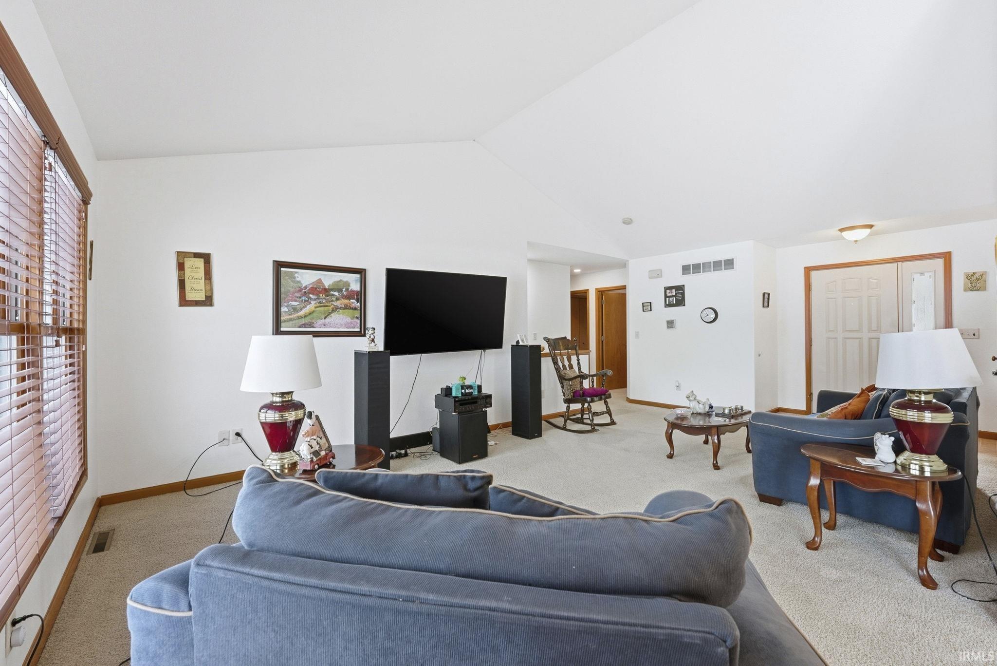 Carpeted living room featuring vaulted ceiling and baseboards