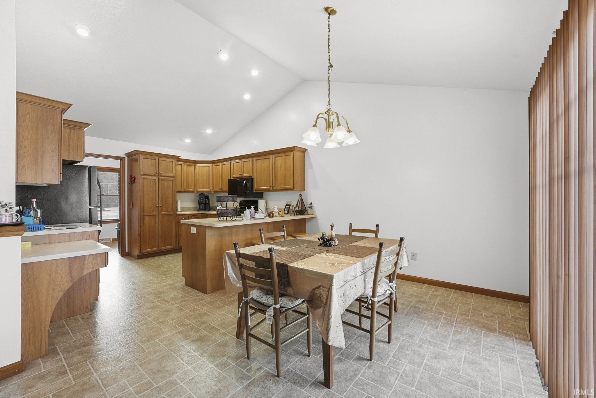 Dining space with vaulted ceiling, stone finish flooring, and a chandelier