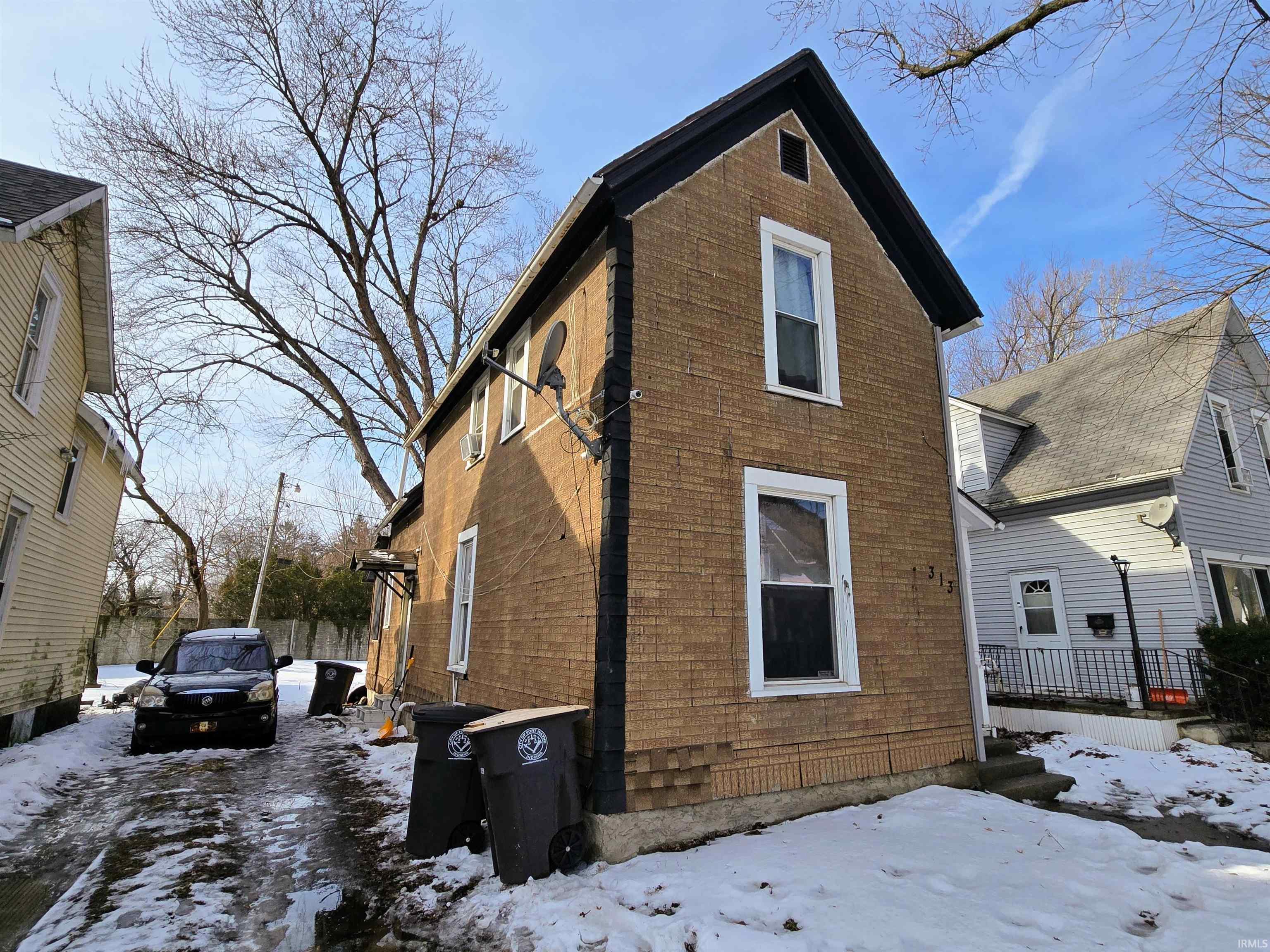 Snow covered back of property with brick siding