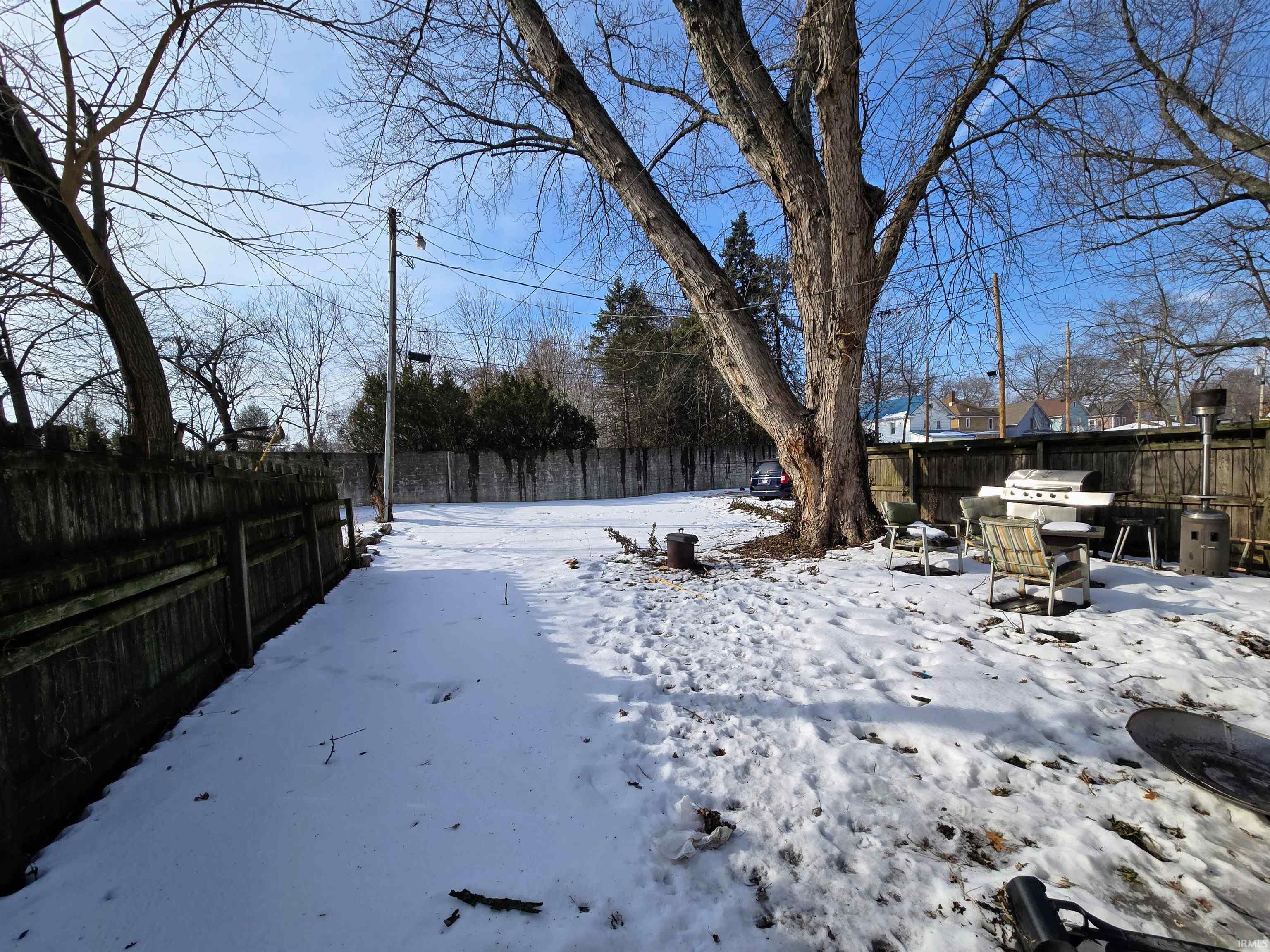 Snowy yard with a fenced backyard