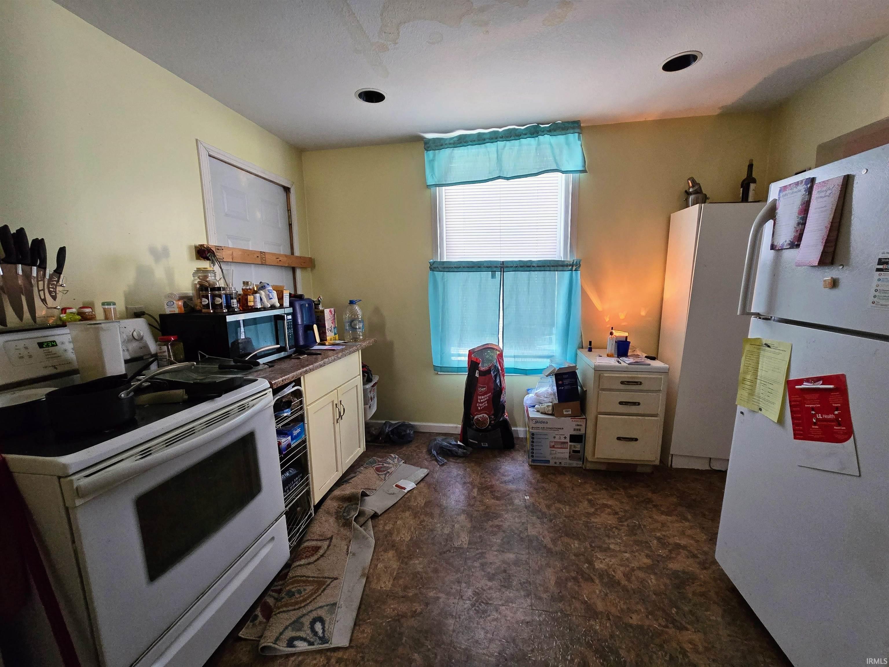 Kitchen featuring white appliances, white cabinets, and dark countertops
