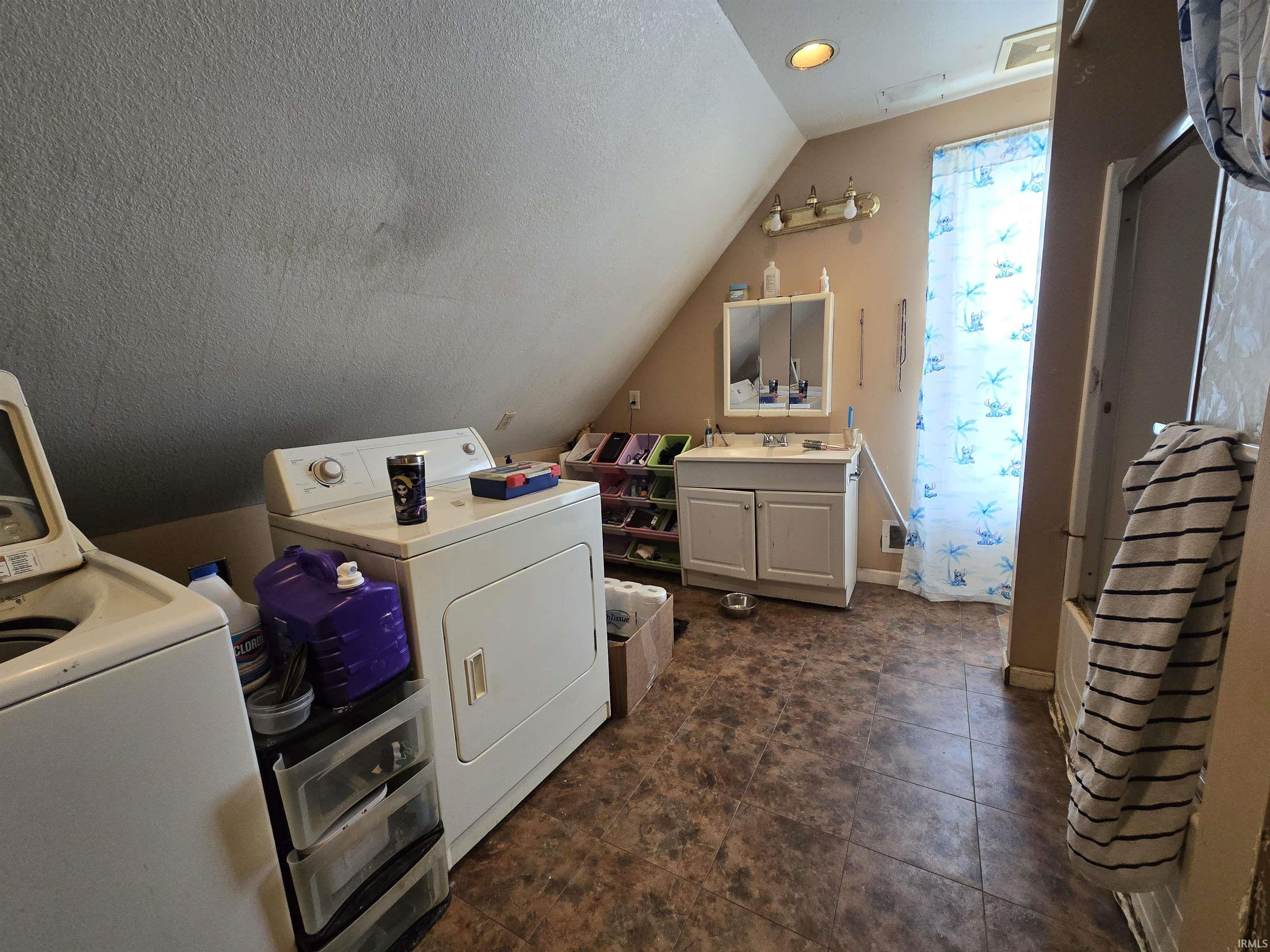 Laundry area featuring washing machine and dryer, recessed lighting, and dark tile patterned flooring