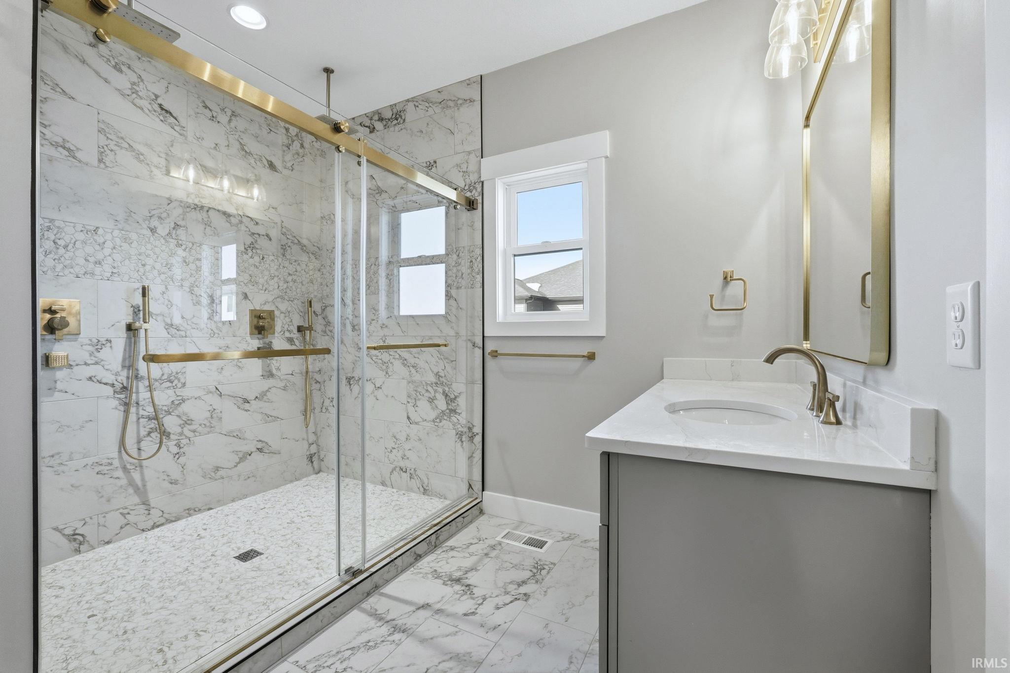 Bathroom featuring a marble finish shower, vanity, and light marble finish flooring