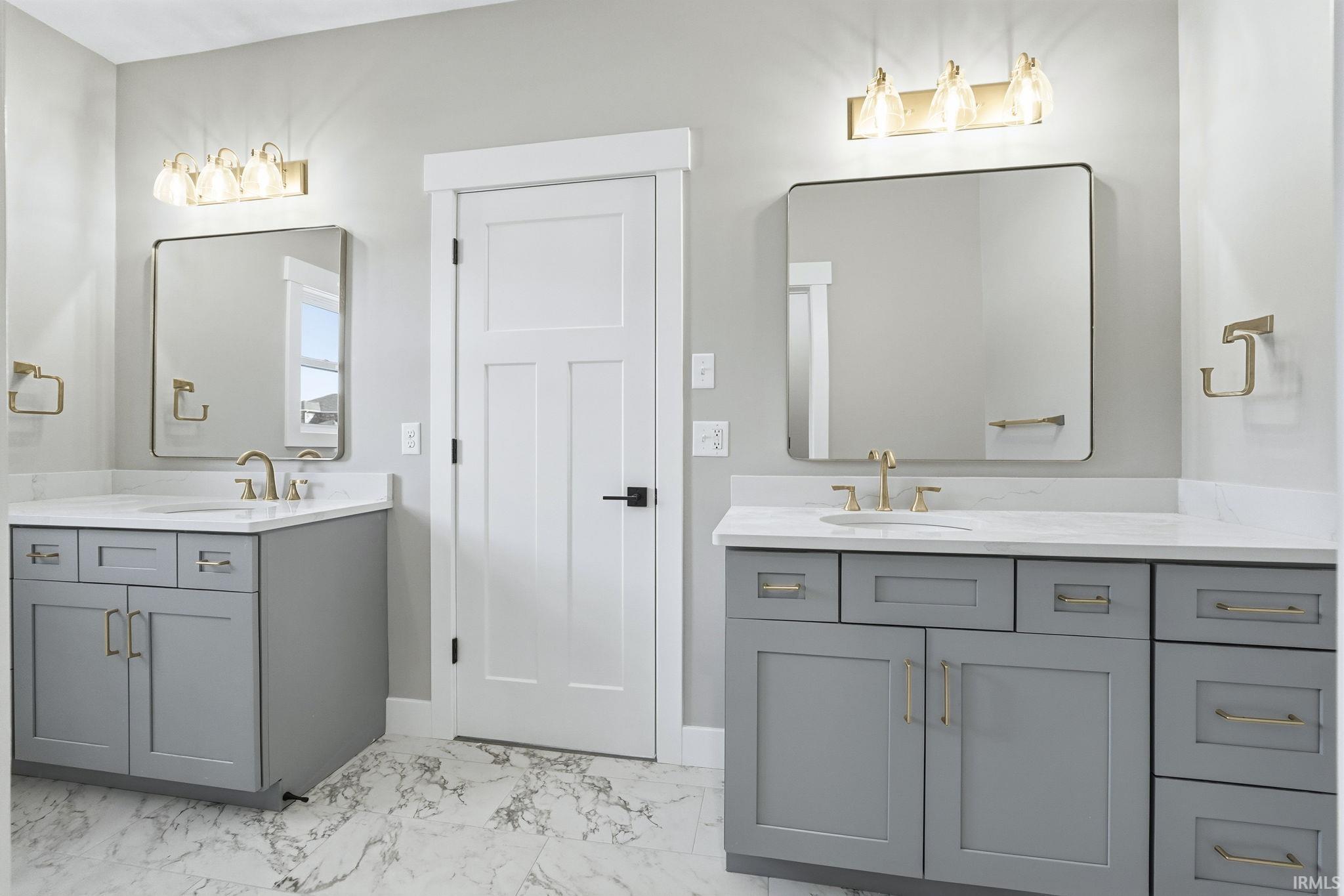 Full bath featuring two vanities and light marble finish flooring