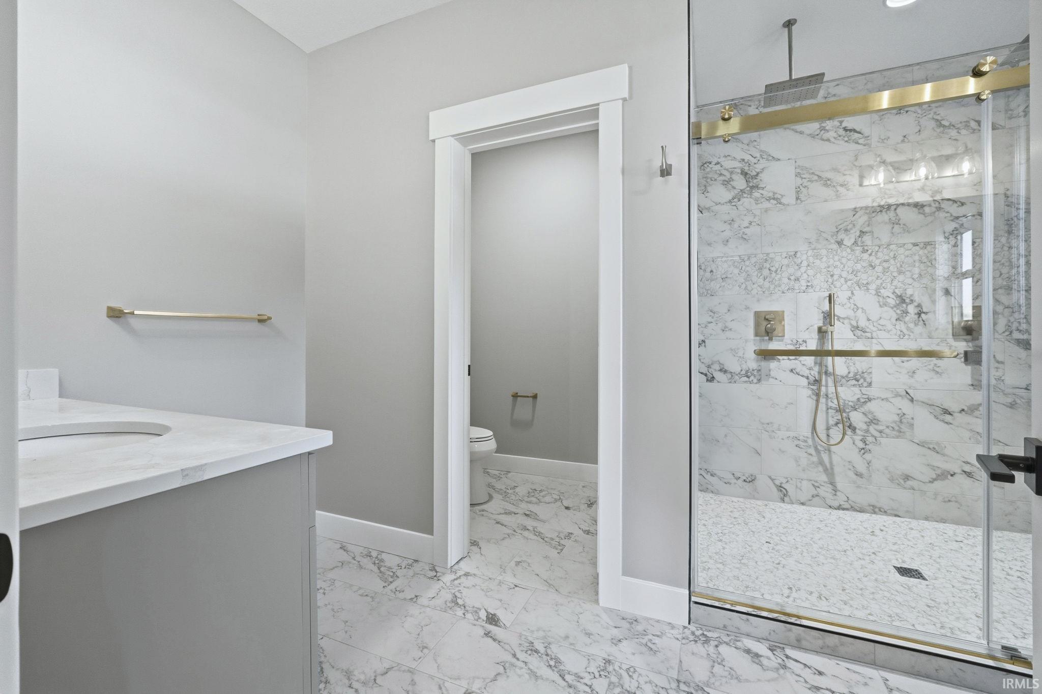 Full bathroom featuring vanity, light marble finish floors, and a marble finish shower