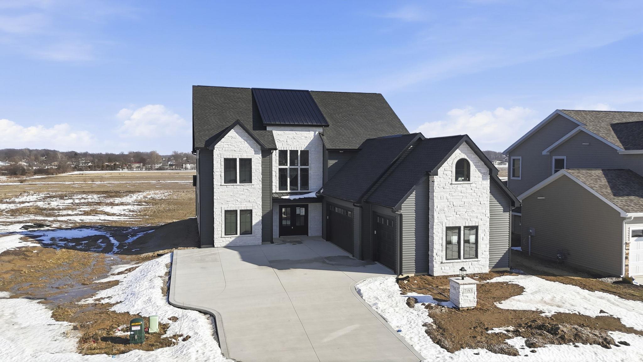 View of front of property with stone siding, driveway, and a garage