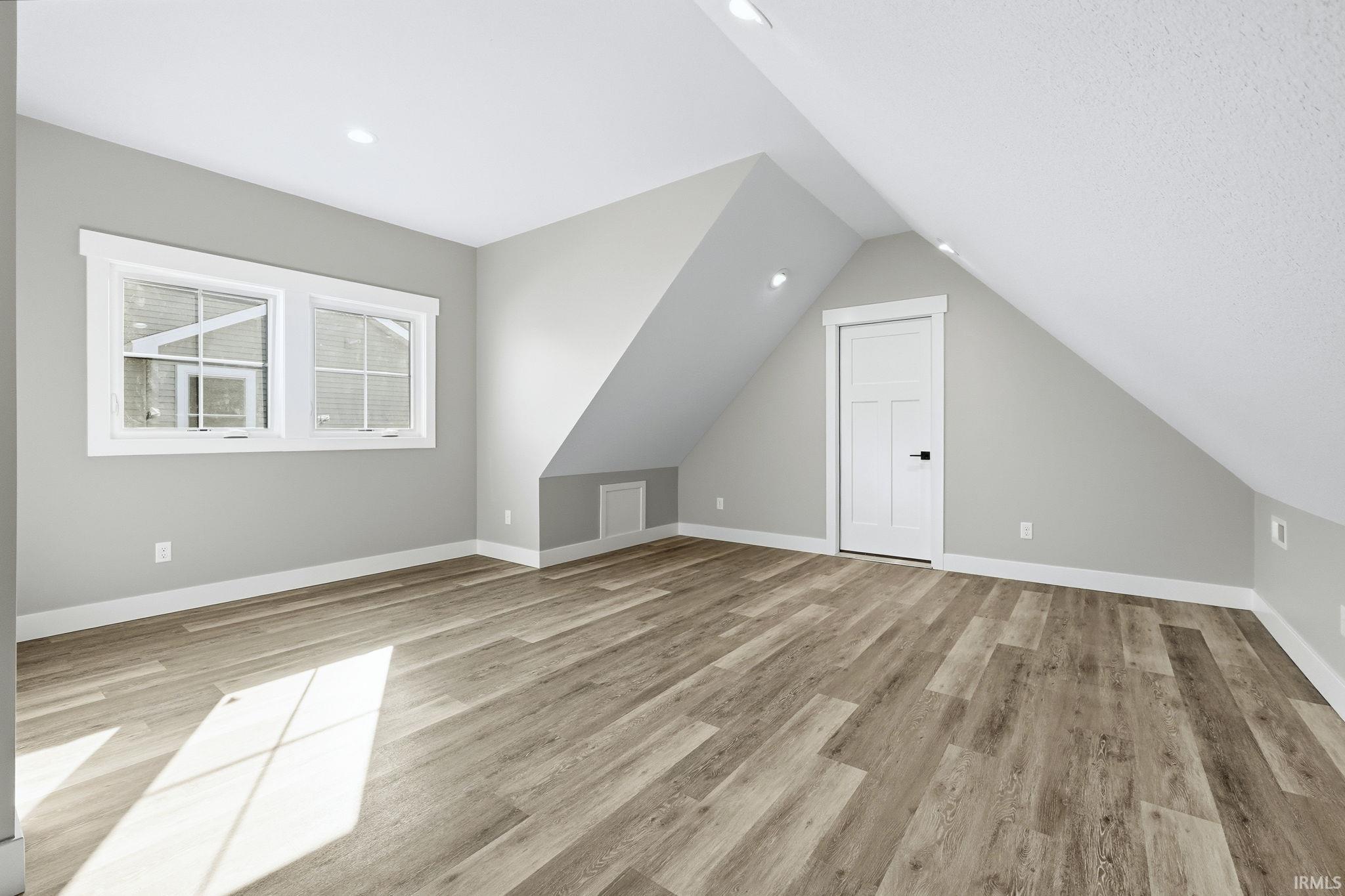 Additional living space with light wood-type flooring and lofted ceiling