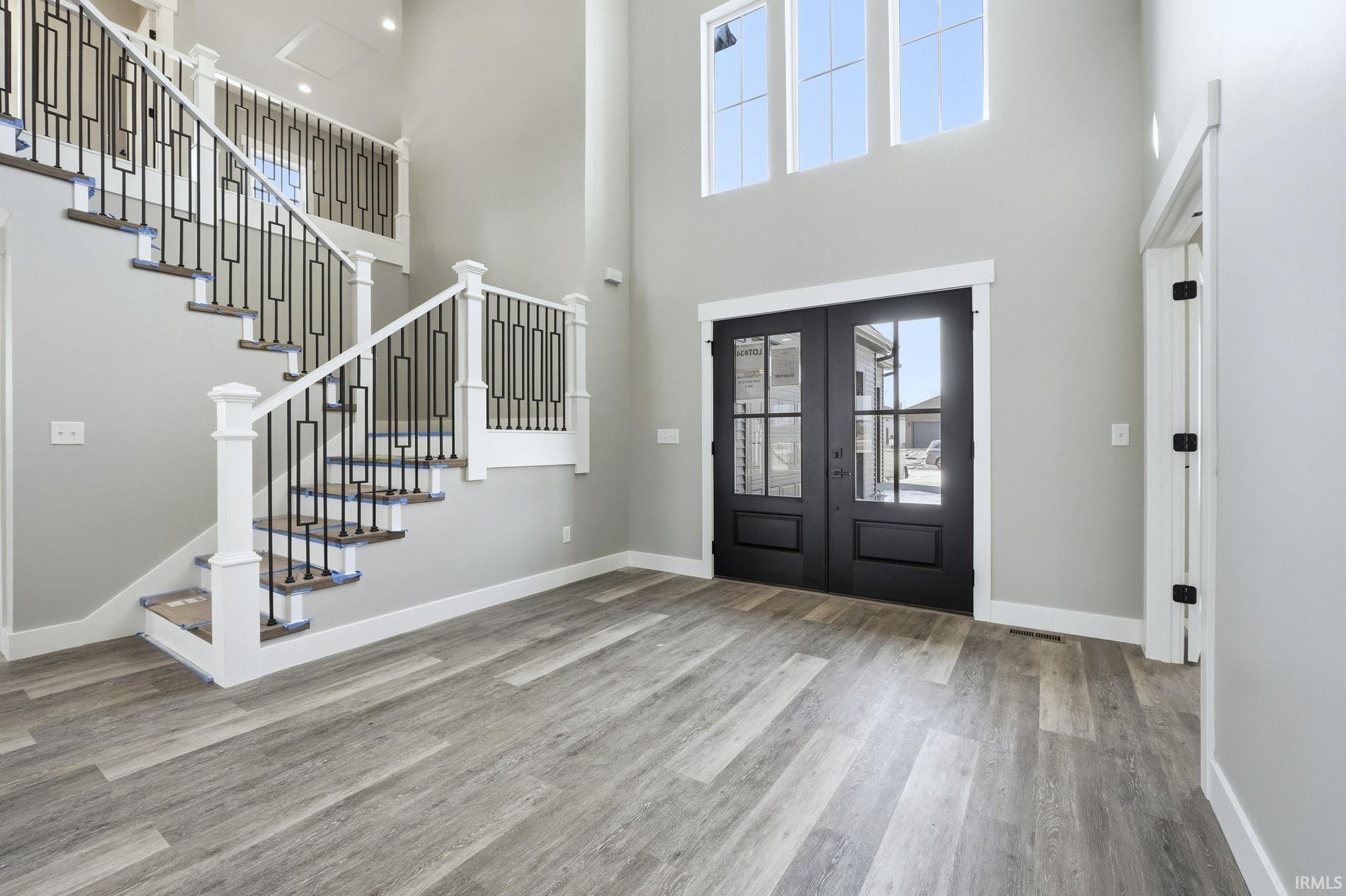 Entryway featuring french doors, light wood-style floors, and a high ceiling
