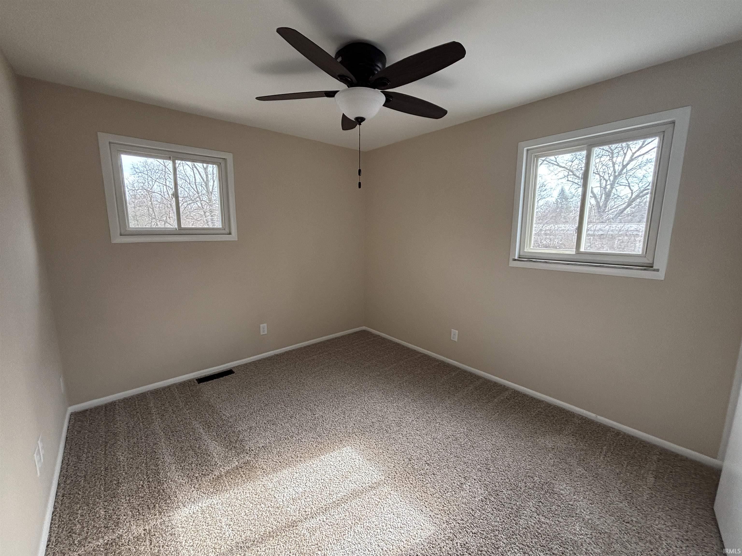 Unfurnished room with light colored carpet and a ceiling fan