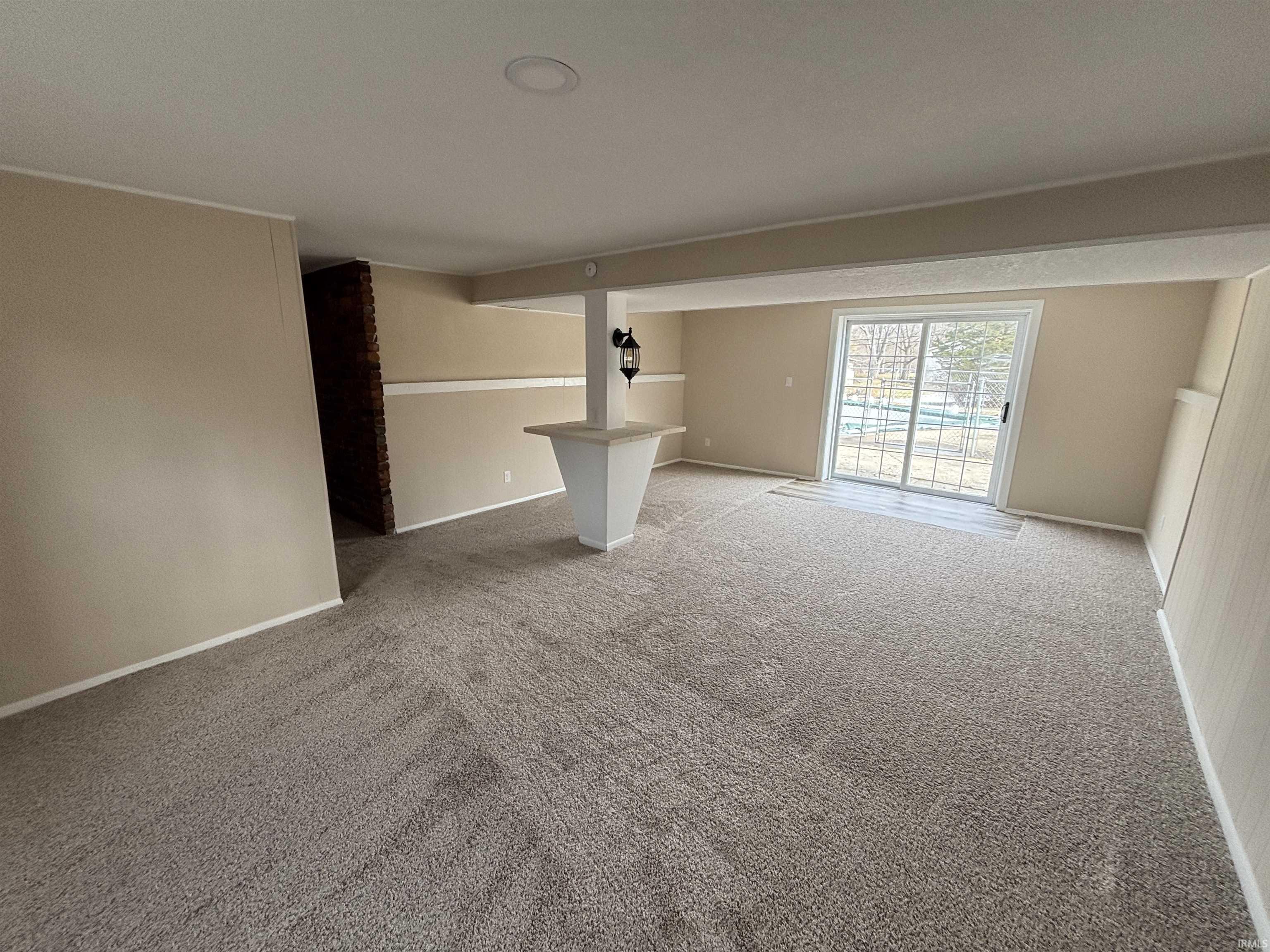 Unfurnished living room featuring carpet and baseboards