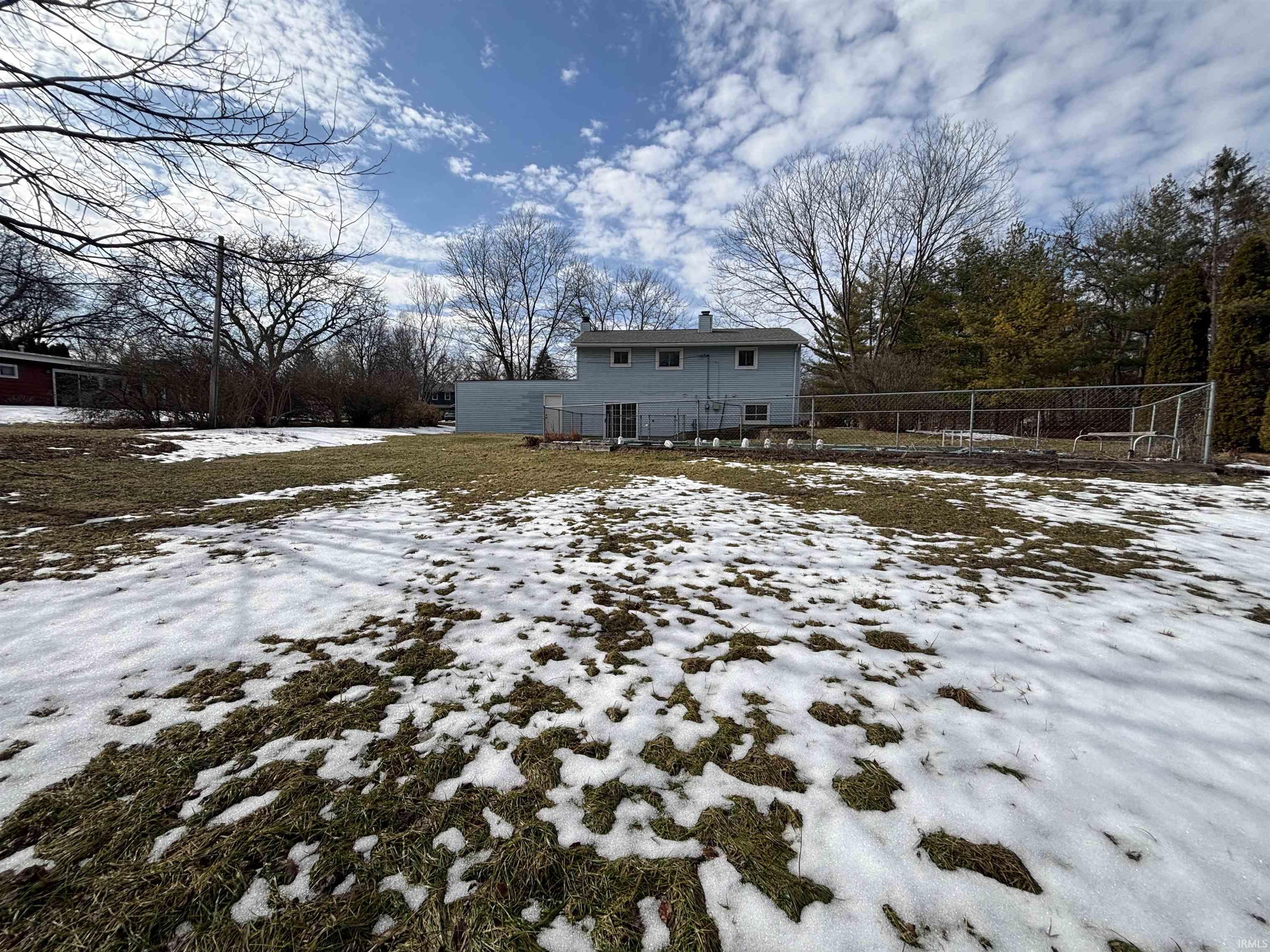 Snow covered rear of property with a chimney