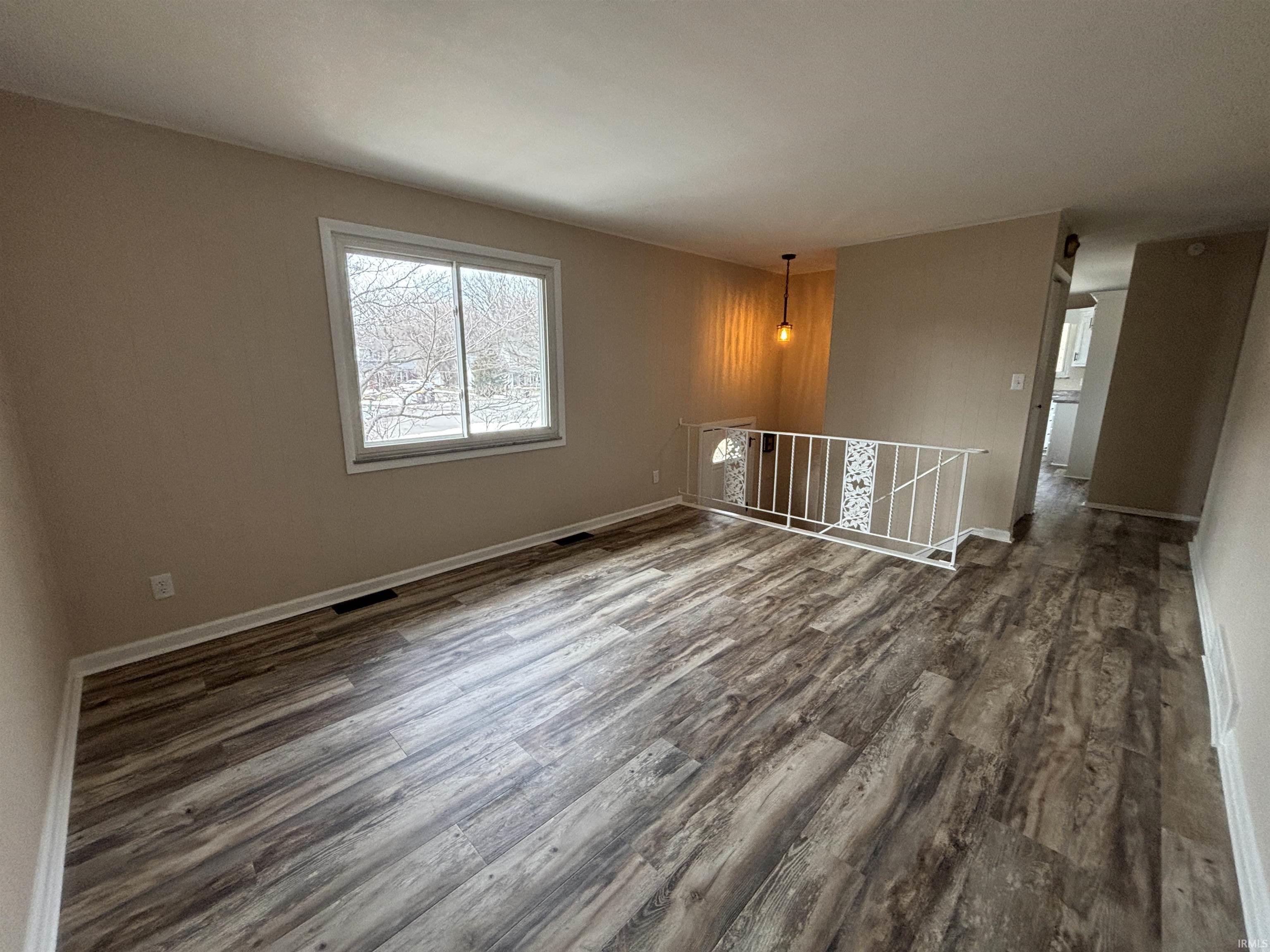 Unfurnished room featuring dark wood-style flooring and baseboards