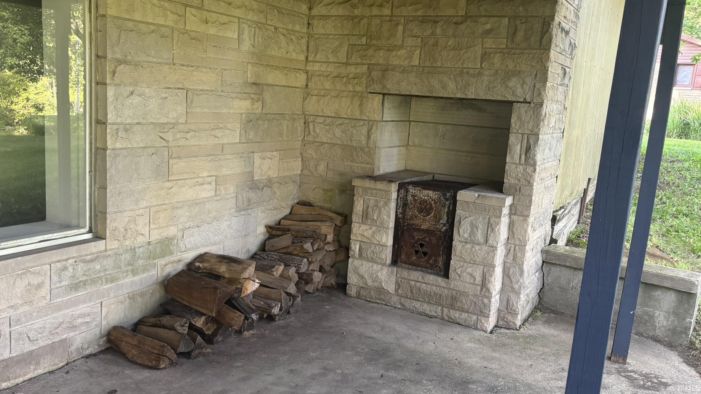 Stone-clad exterior featuring a built-in outdoor cooking area with a metal door and a full-height stone surround