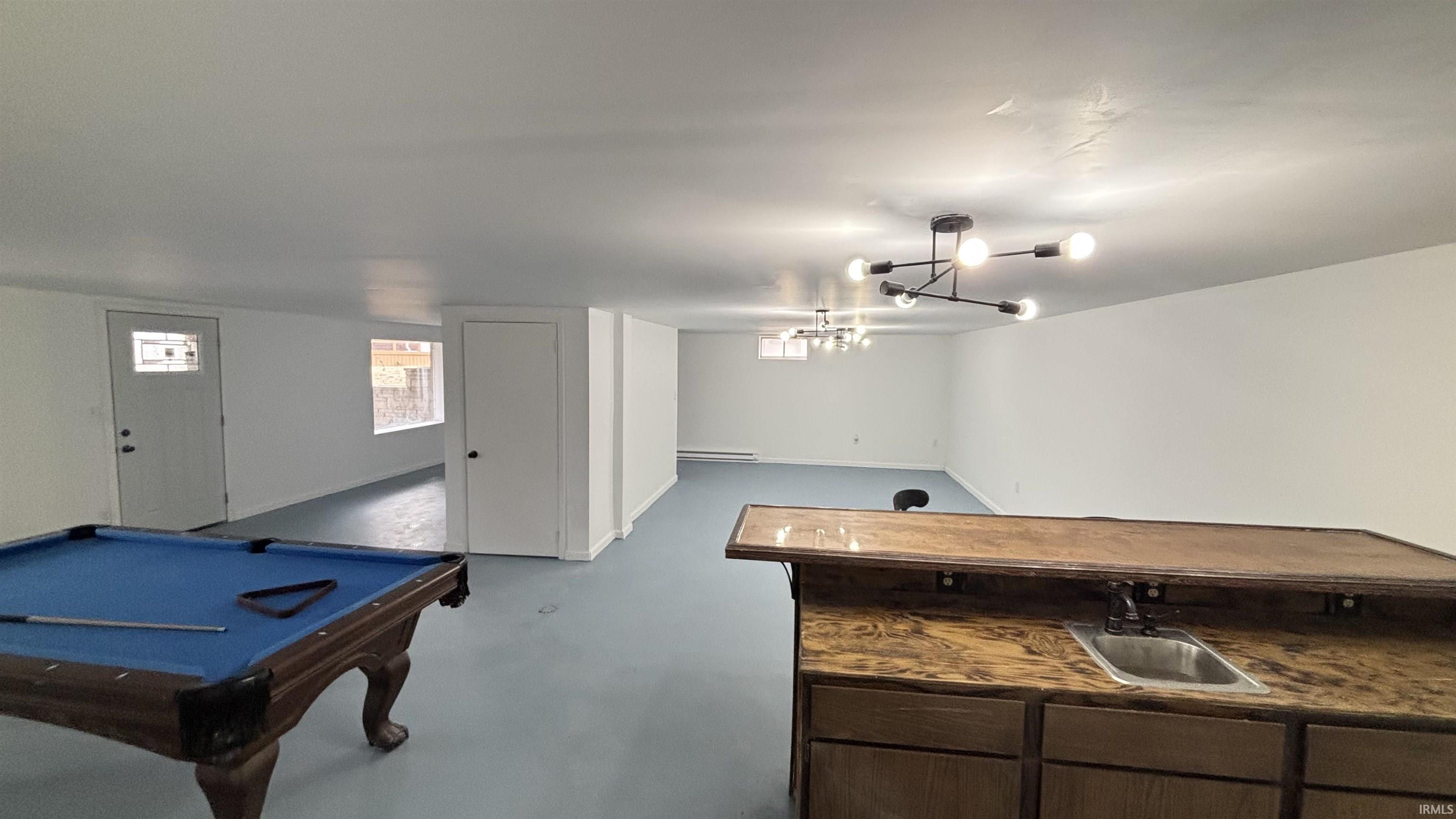 Game room featuring billiards table, bar with sink, concrete floors, and a baseboard heating unit