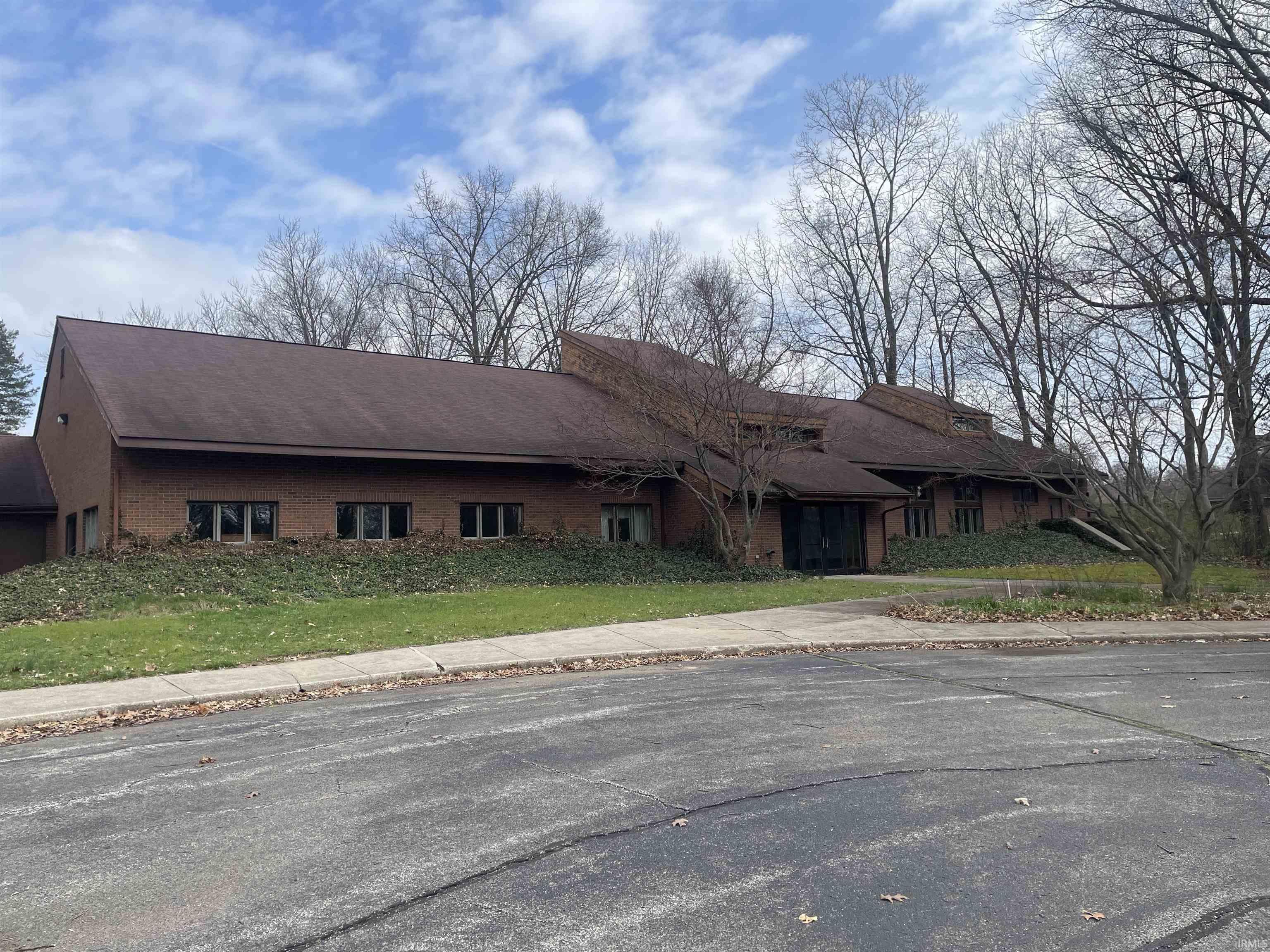 View of front of home featuring brick siding and roof with shingles