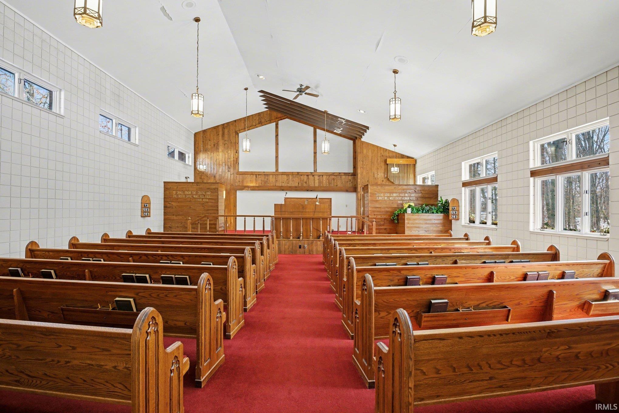 Misc room featuring a high ceiling, a ceiling fan, and wooden walls