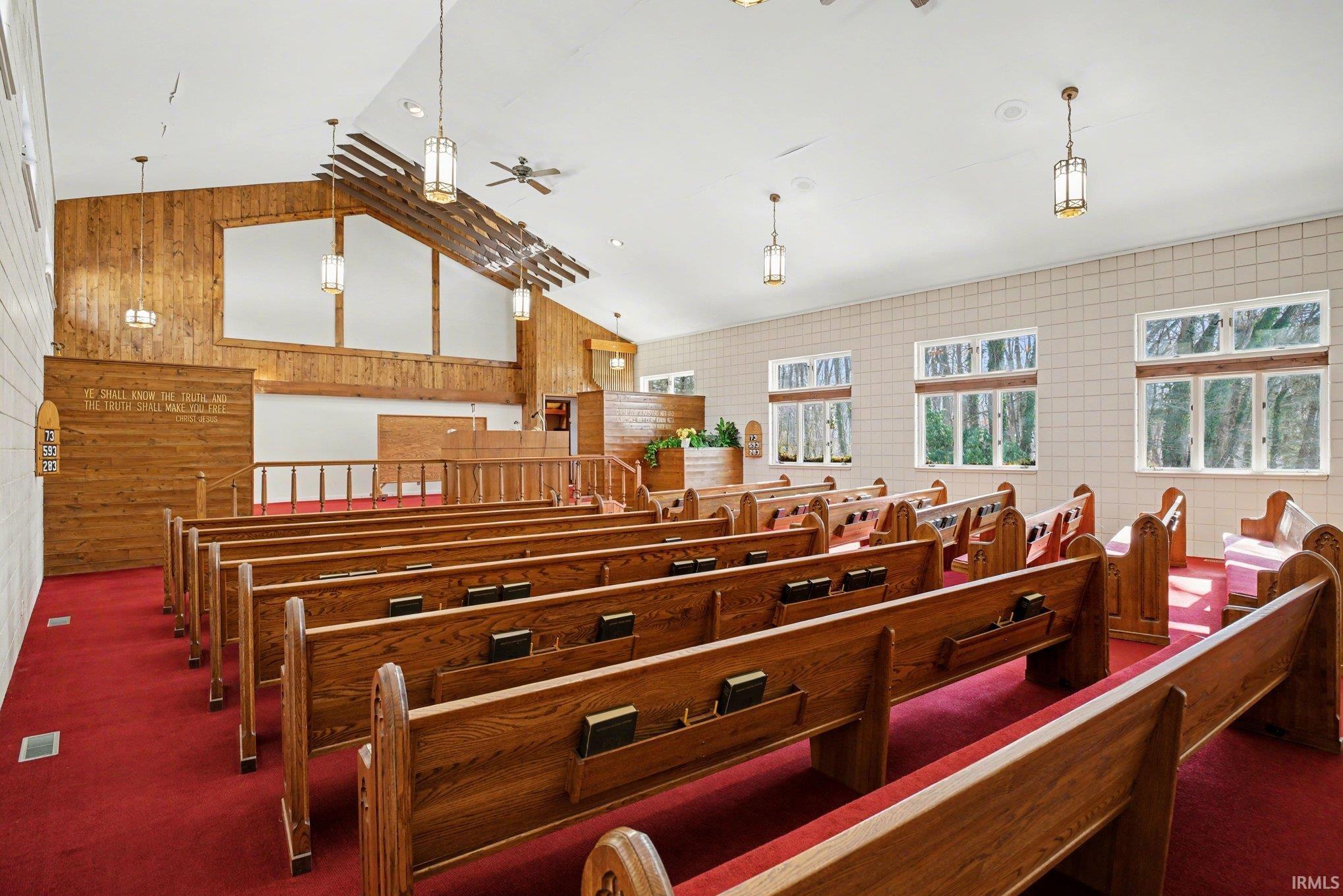Misc room featuring a high ceiling, wooden walls, and a ceiling fan