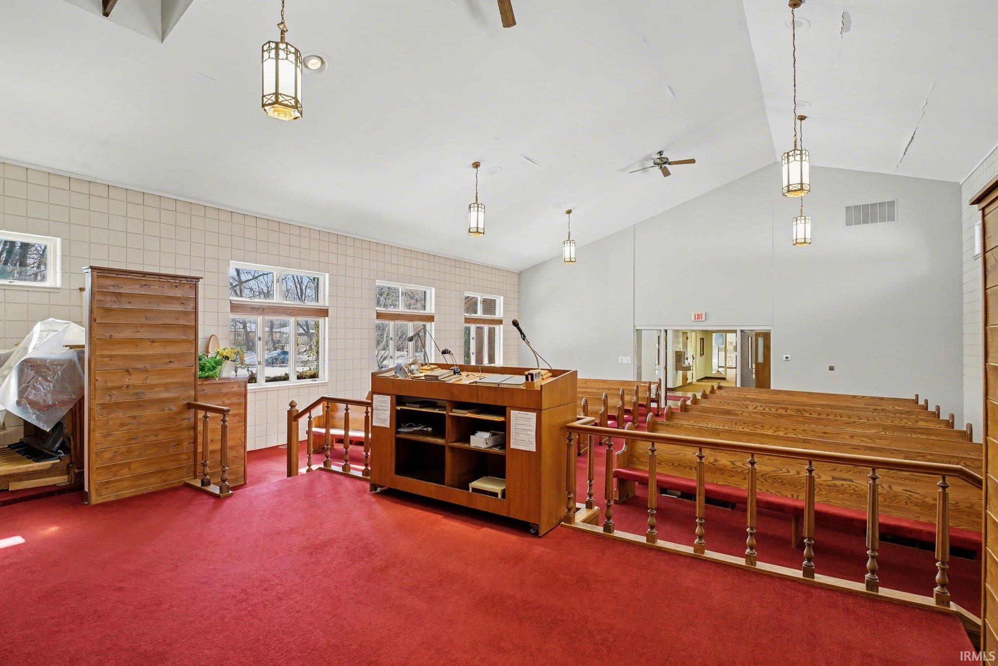 Misc room with carpet, a high ceiling, an upstairs landing, and a ceiling fan