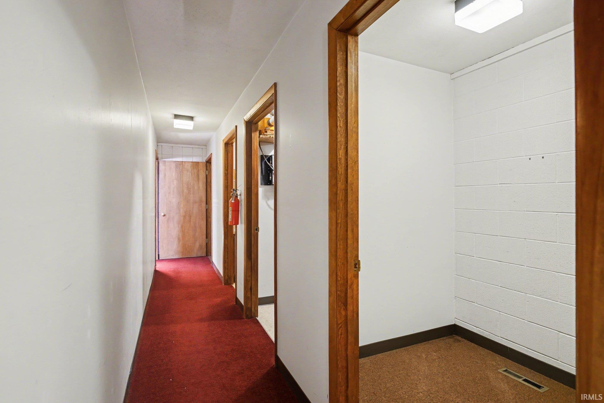 Corridor featuring dark colored carpet and baseboards