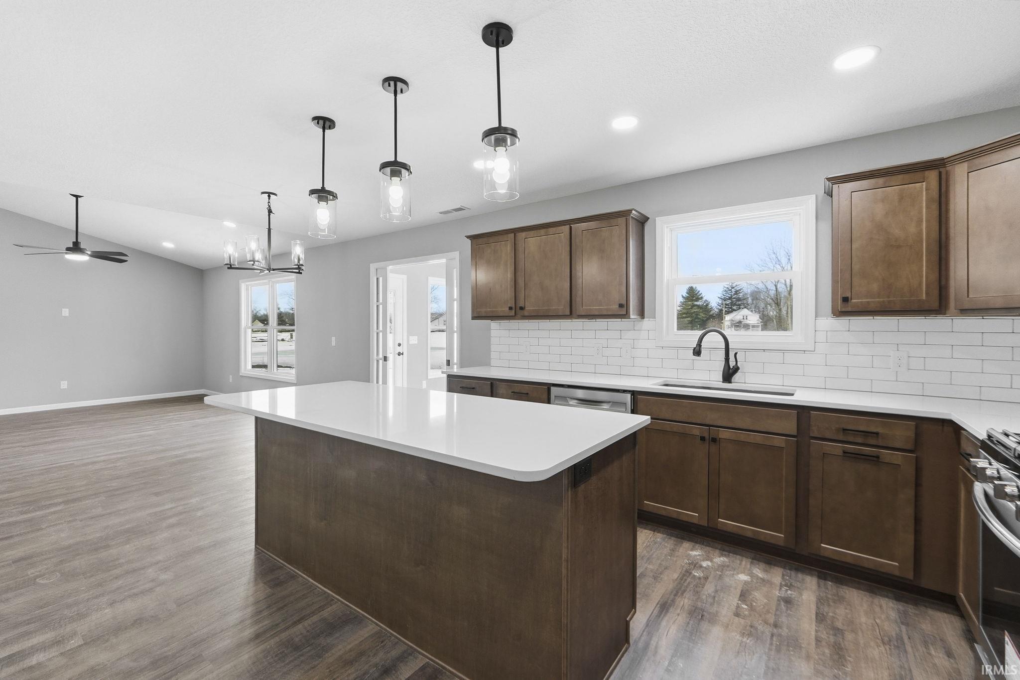 Kitchen featuring backsplash, a center island, healthy amount of natural light, stainless steel appliances, and lofted ceiling