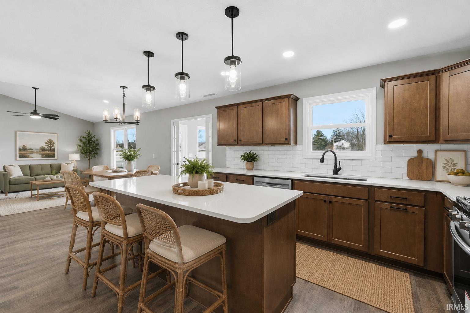 Open concept kitchen featuring an expansive island with a solid surface countertop, wood-finish cabinetry, subway tile backsplash, and stainless steel appliances