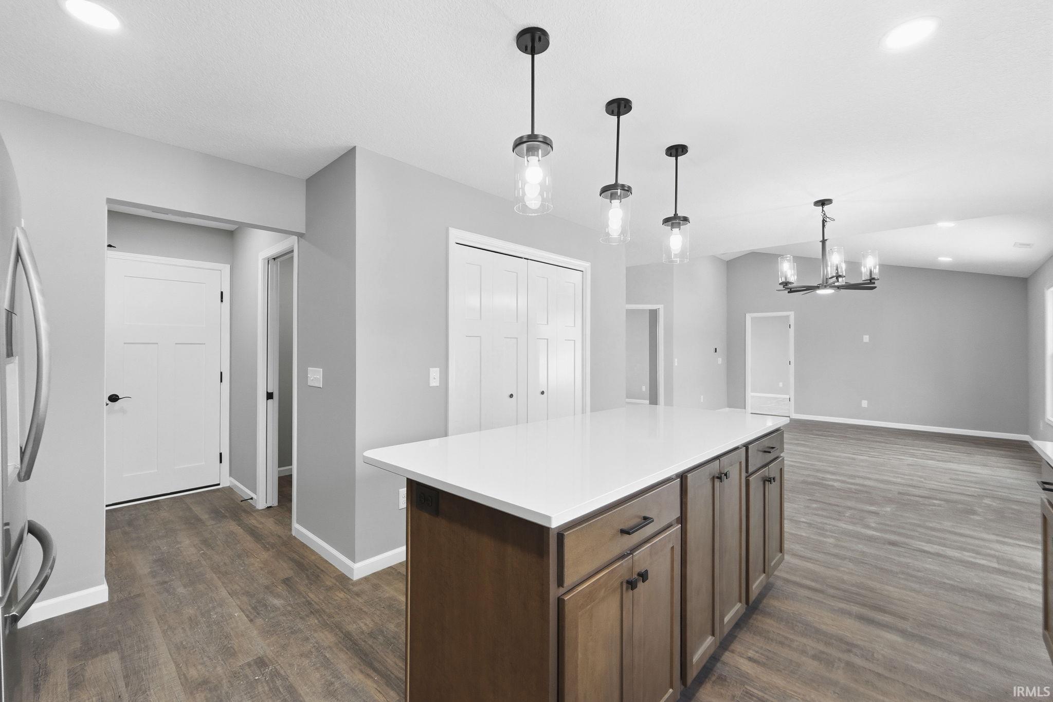 Kitchen with a kitchen island, dark wood-style flooring, hanging lights, and stainless steel refrigerator