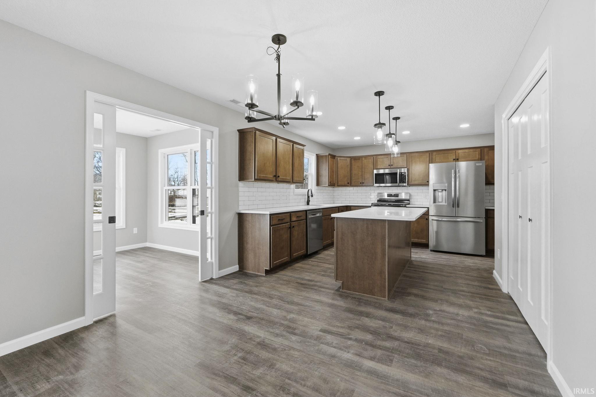 Kitchen with a kitchen island, light countertops, stainless steel appliances, a chandelier, and decorative backsplash
