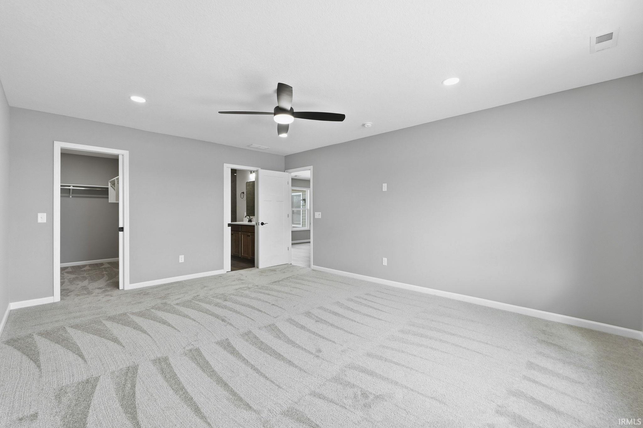 Unfurnished bedroom featuring a spacious closet, connected bathroom, a ceiling fan, light carpet, and recessed lighting
