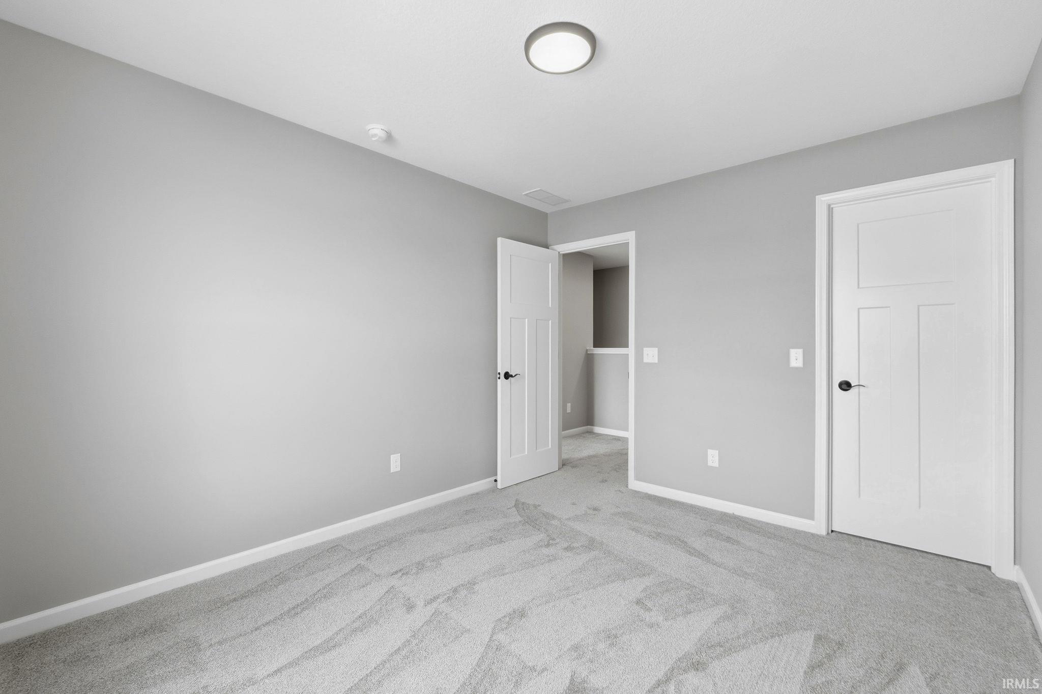 Unfurnished bedroom with baseboards and light colored carpet
