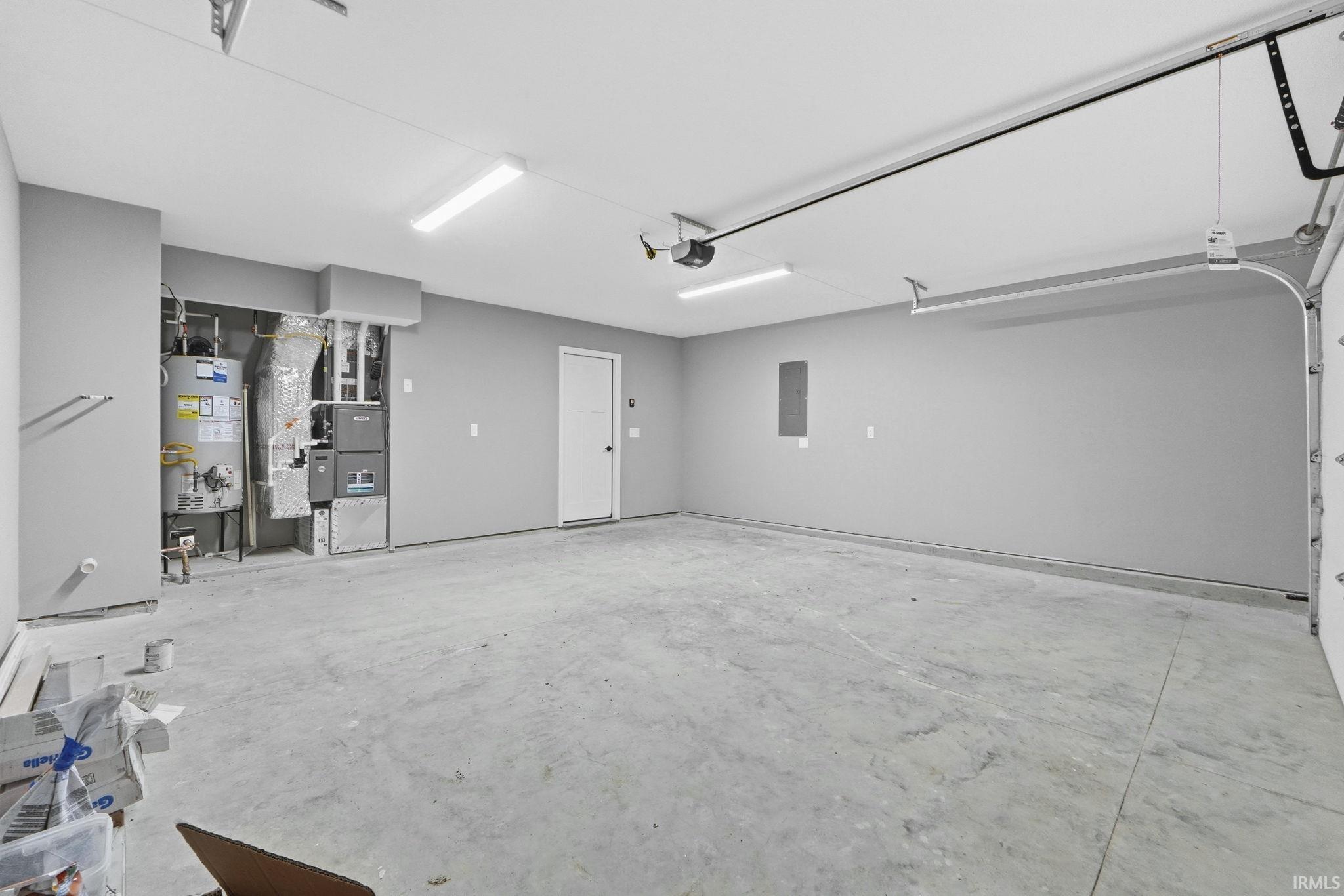 Garage featuring heating unit, water heater, and electric panel