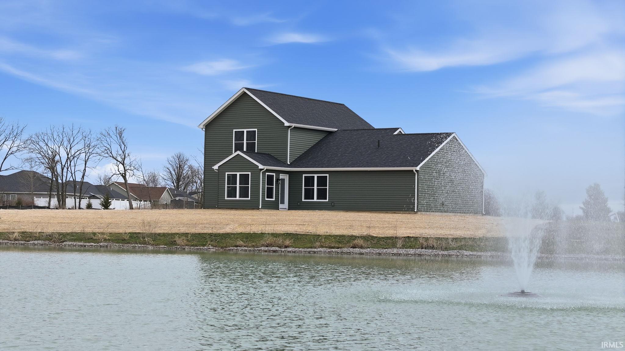 Rear view of house with roof with shingles, a water view, and a yard