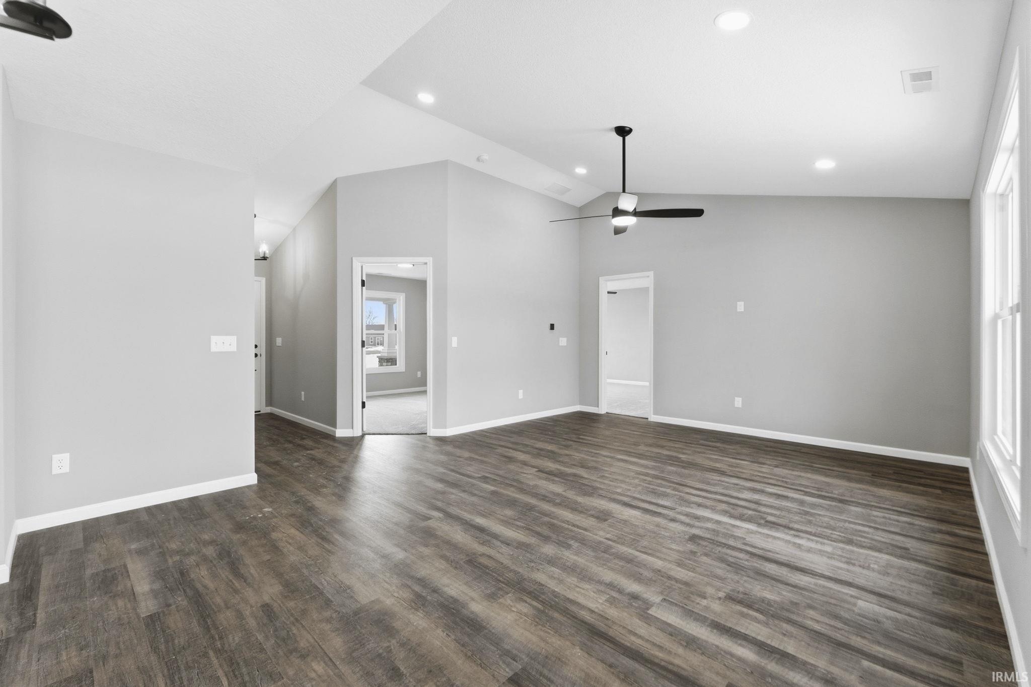 Unfurnished living room featuring a ceiling fan, dark wood finished floors, vaulted ceiling, and recessed lighting