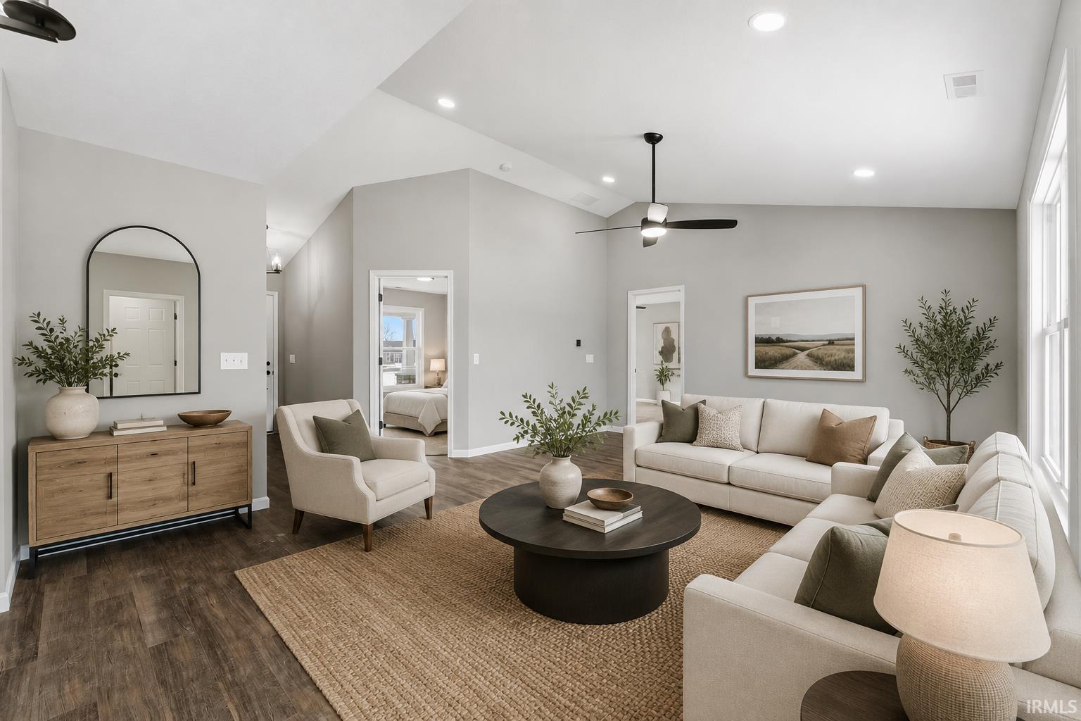 Spacious living area featuring vaulted ceilings, recessed lighting, wood-finish flooring, and multiple windows